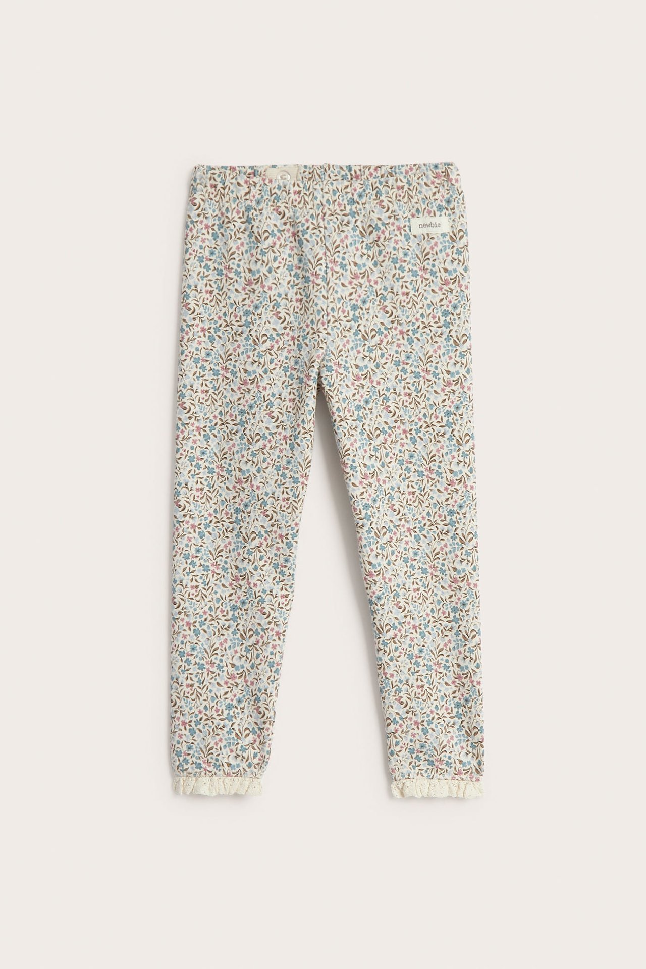 Vorderansicht von Baby-Leggings in Beige mit Blumenmuster und Rüschenspitze.