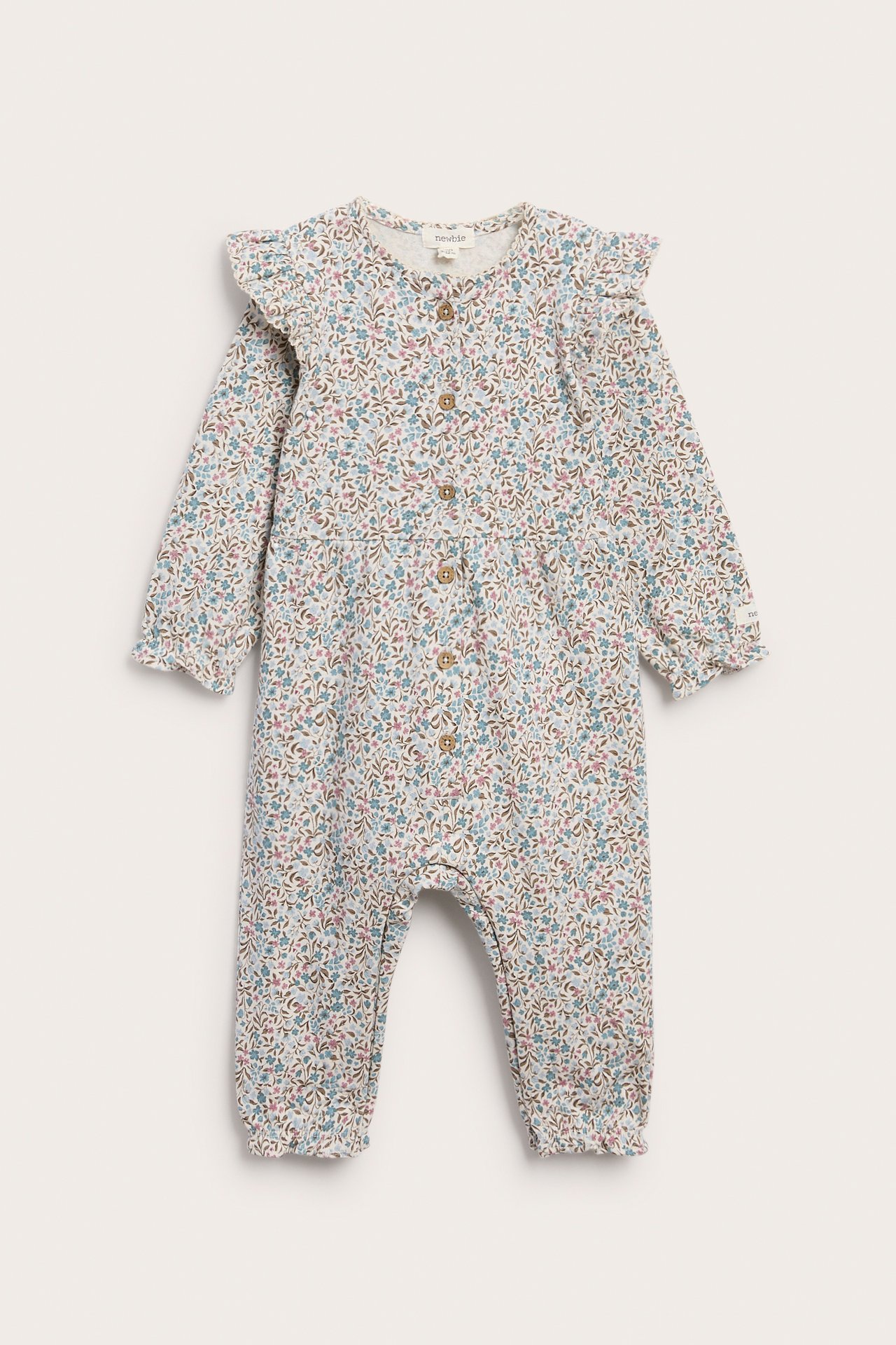 Vorderansicht eines weißen Baby-Blumenstramplers mit langen Ärmeln, Rüschenschultern und Knopfleiste.