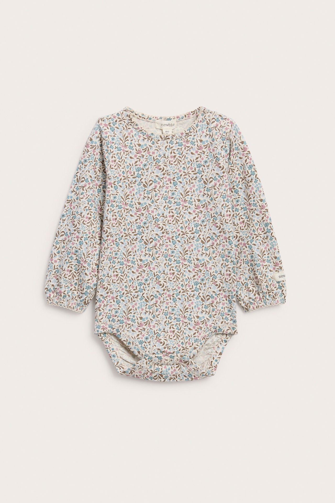 Vorderansicht eines Baby-Langarm-Bodys mit Blumenmuster in Blau, Rosa und Braun auf Creme.