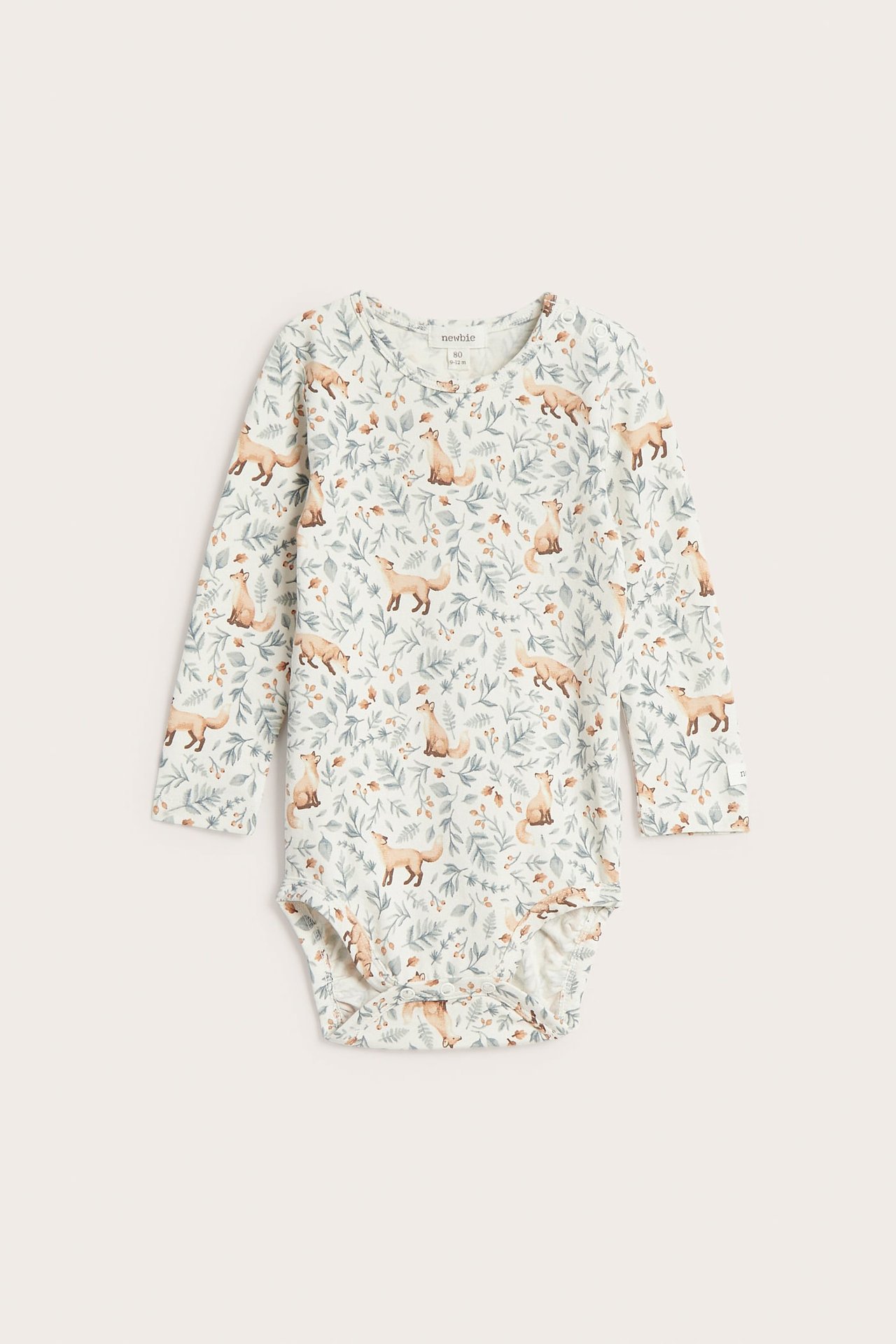 Front view of a white baby long-sleeved bodysuit with a fox and foliage print.