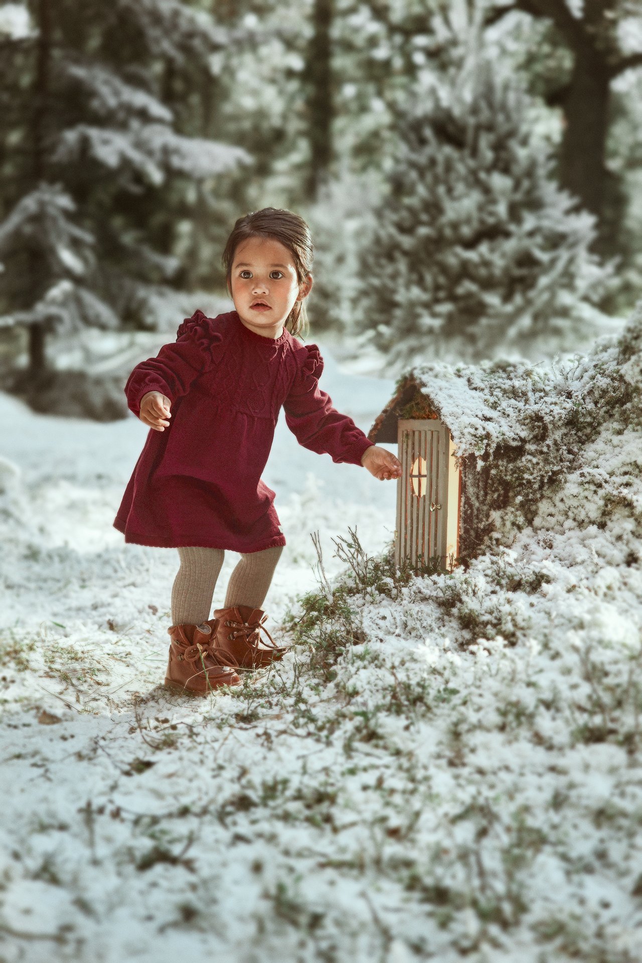 Front view of a kid wearing a maroon knit dress, light brown tights, and brown lace-up boots.