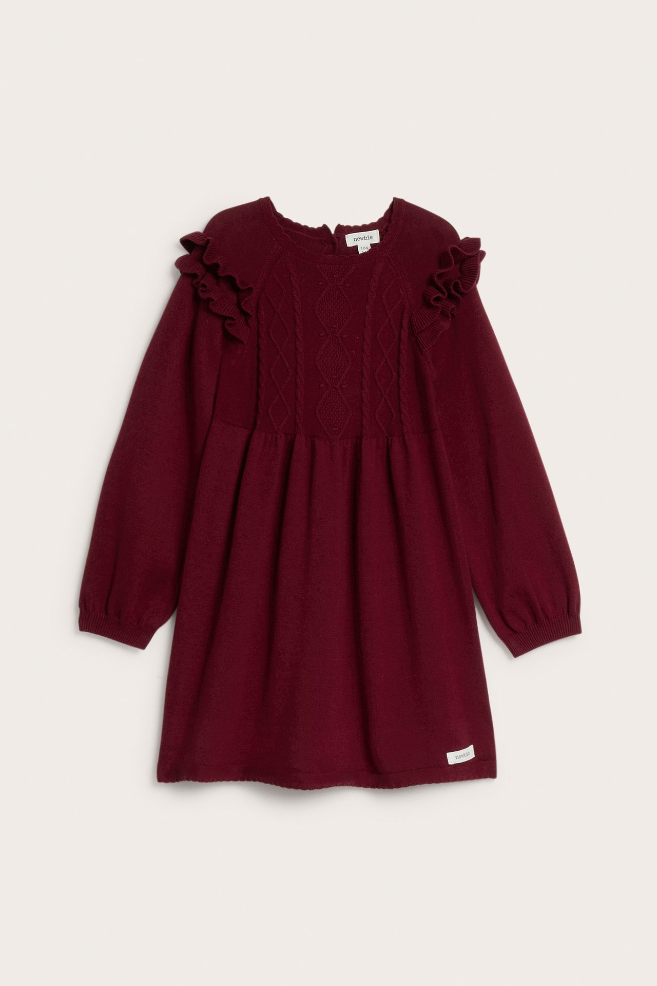 Front view of a kid's burgundy knitted dress with ruffled shoulders and cable knit details.