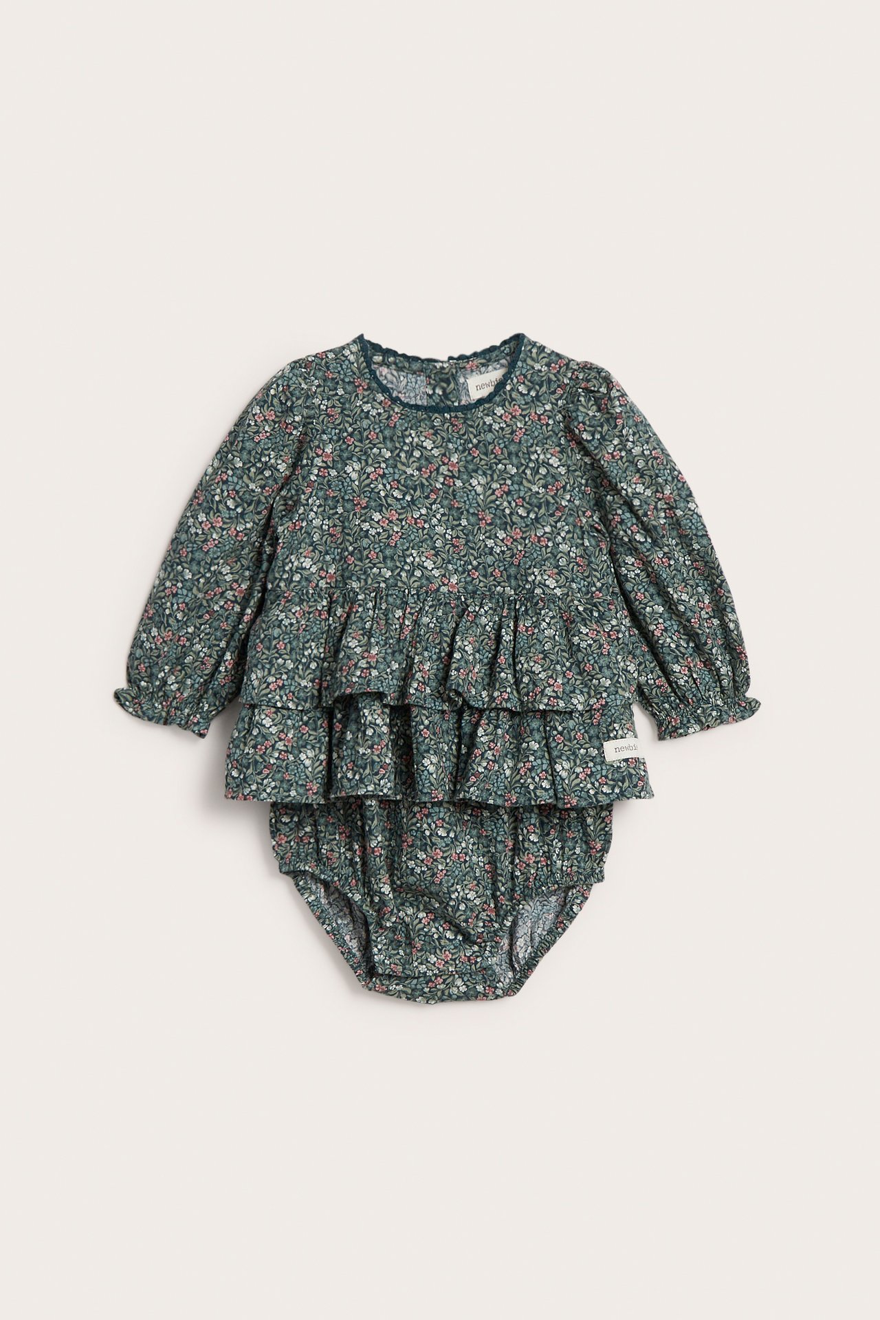 Vorderansicht eines zweiteiligen Baby-Sets mit grünem Blumenmuster, Rüschentop und Bloomer-Hose.