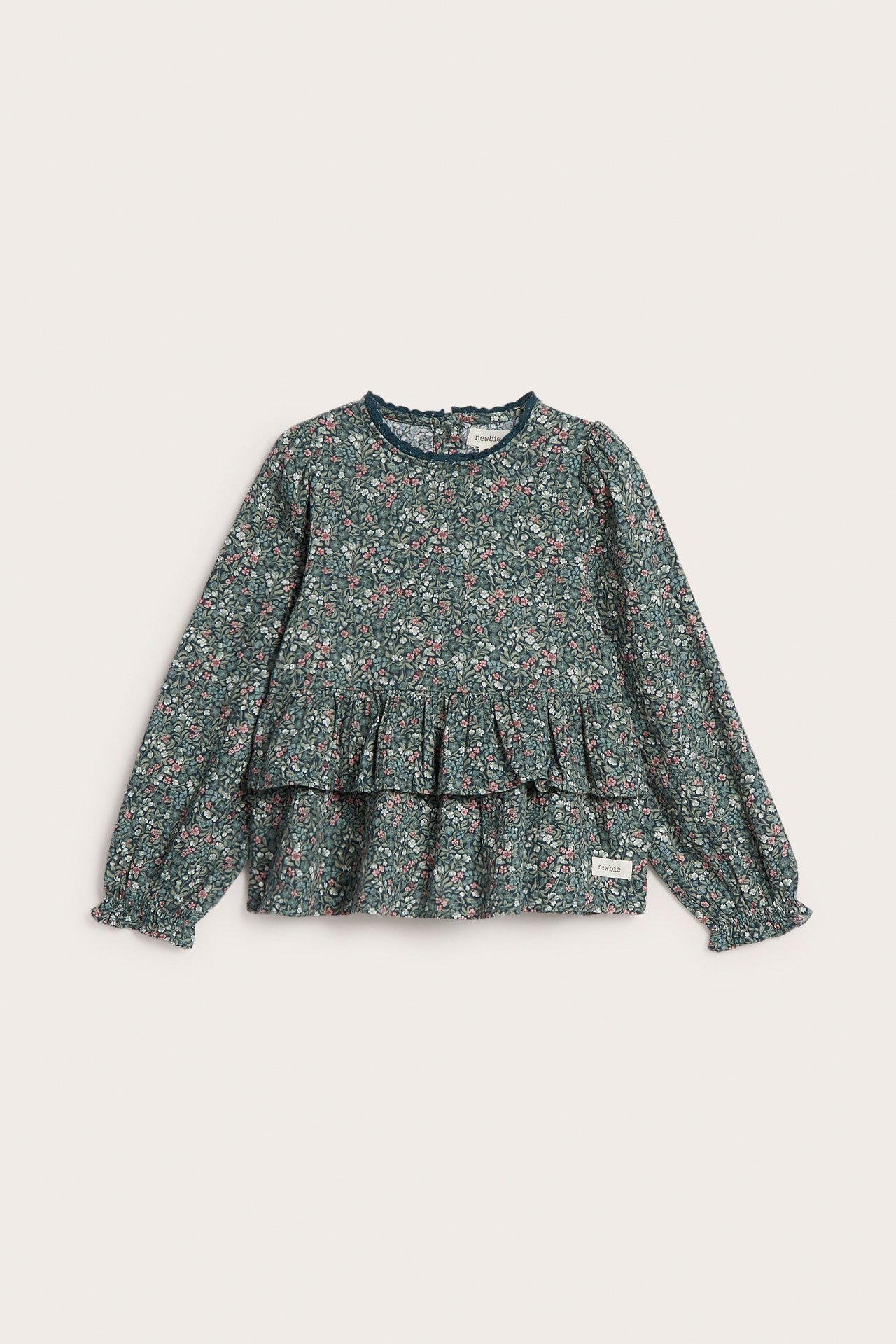 Vorderansicht eines grünen geblümten Langarm-Peplum-Tops für Kinder mit Rüschenkragen und -bündchen.