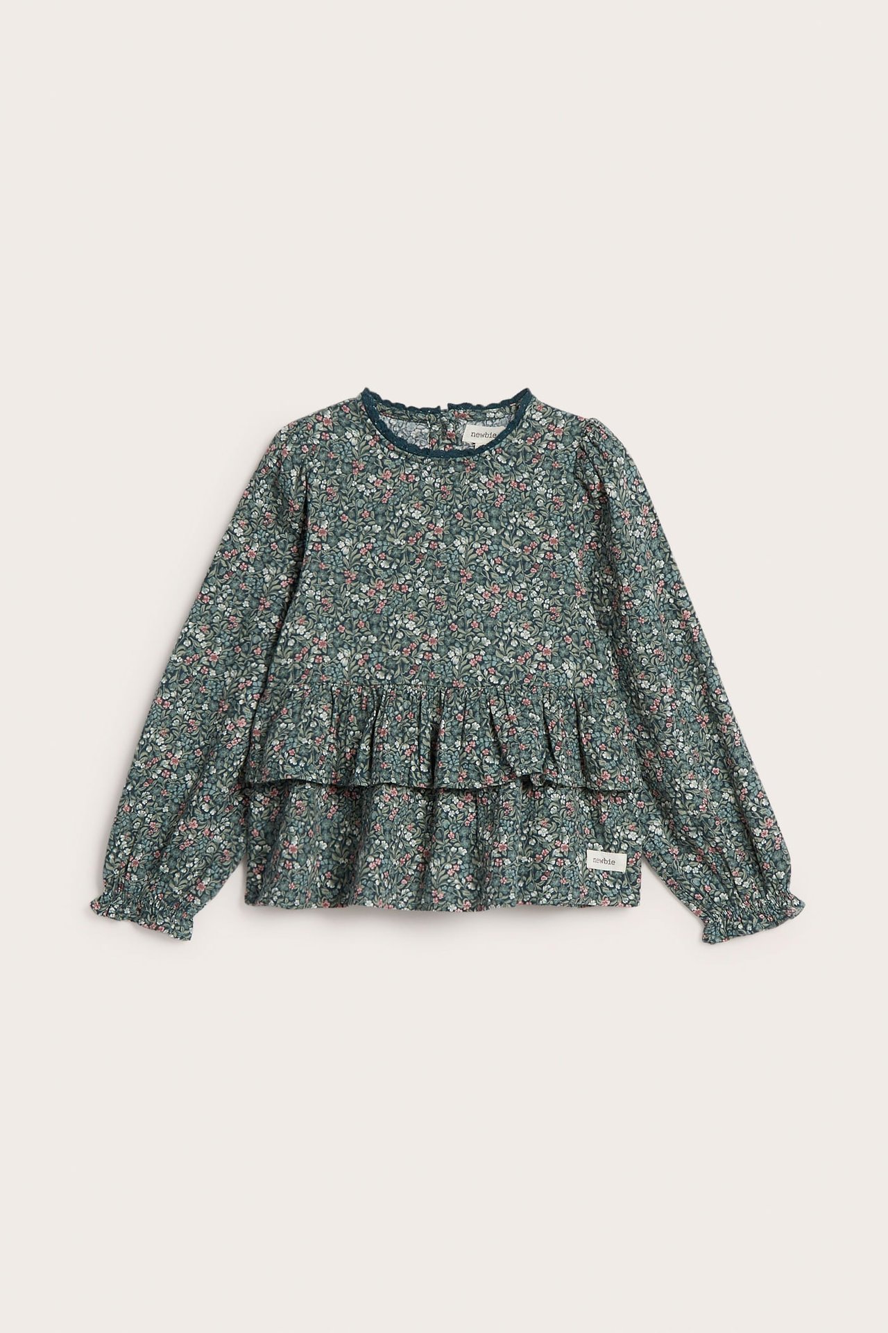 Vorderansicht eines grünen geblümten Langarm-Peplum-Tops für Kinder mit Rüschenkragen und -bündchen.