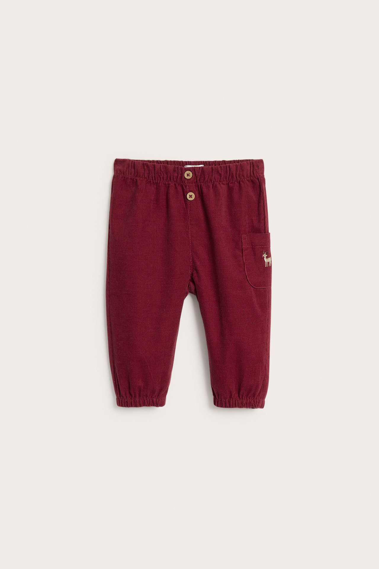 Front view of dark red baby corduroy pants with button details and embroidered deer.