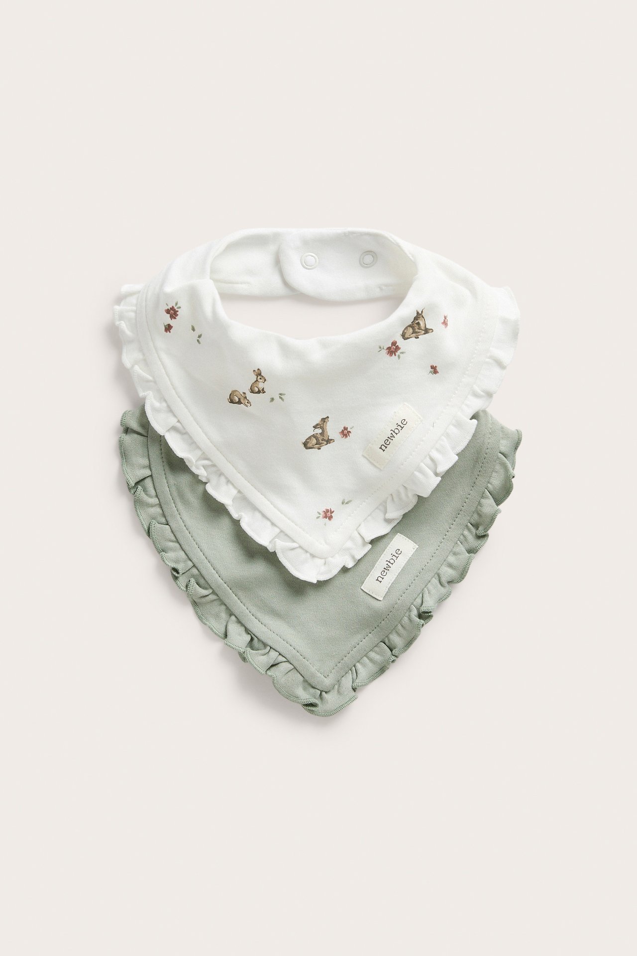 Front view of two baby ruffled bandana bibs, one white with animal print and one sage green.