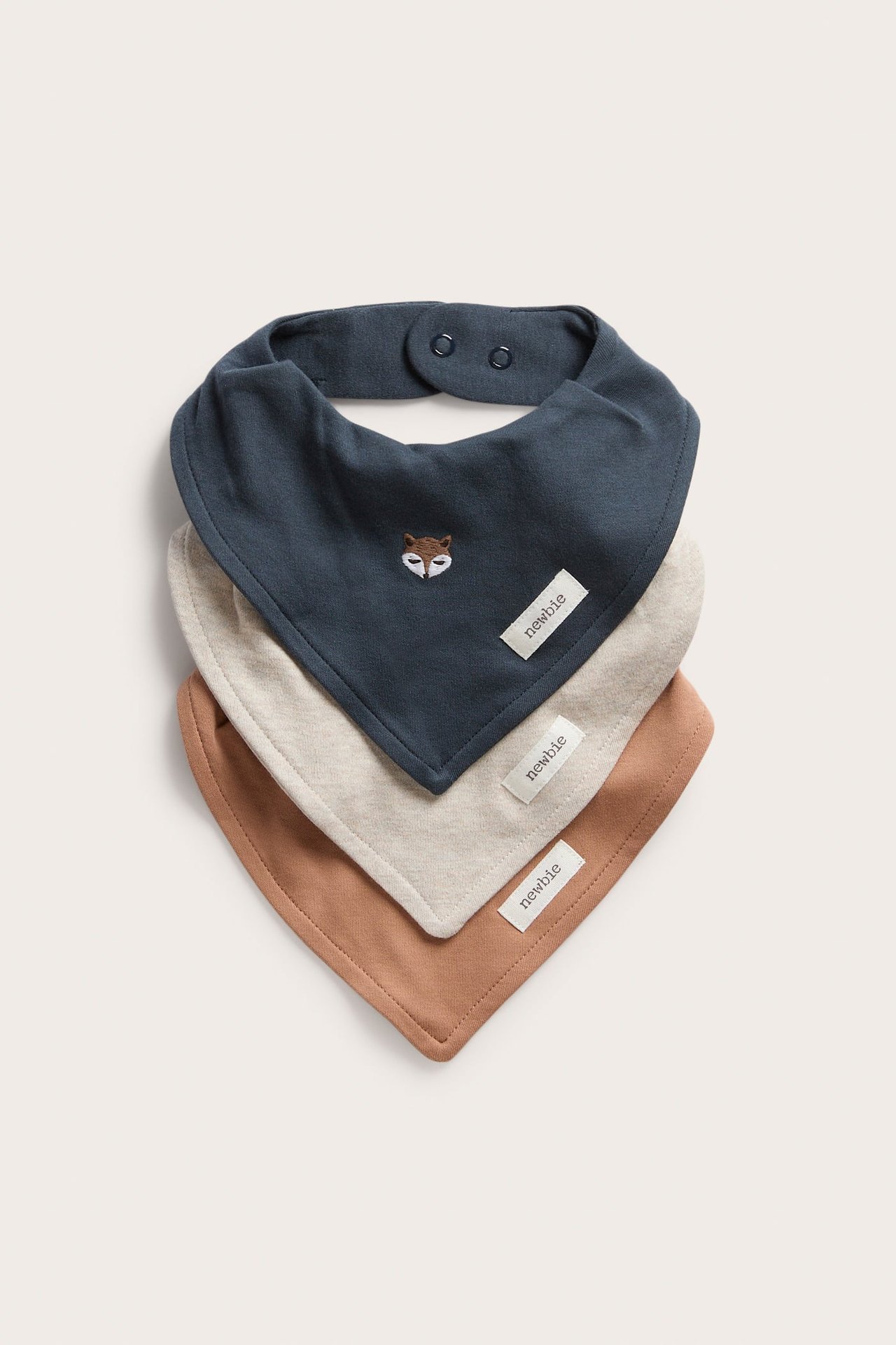 Vorderansicht von drei gestapelten Baby-Halstüchern: dunkelblau mit Fuchs-Stickerei, beige und braun.