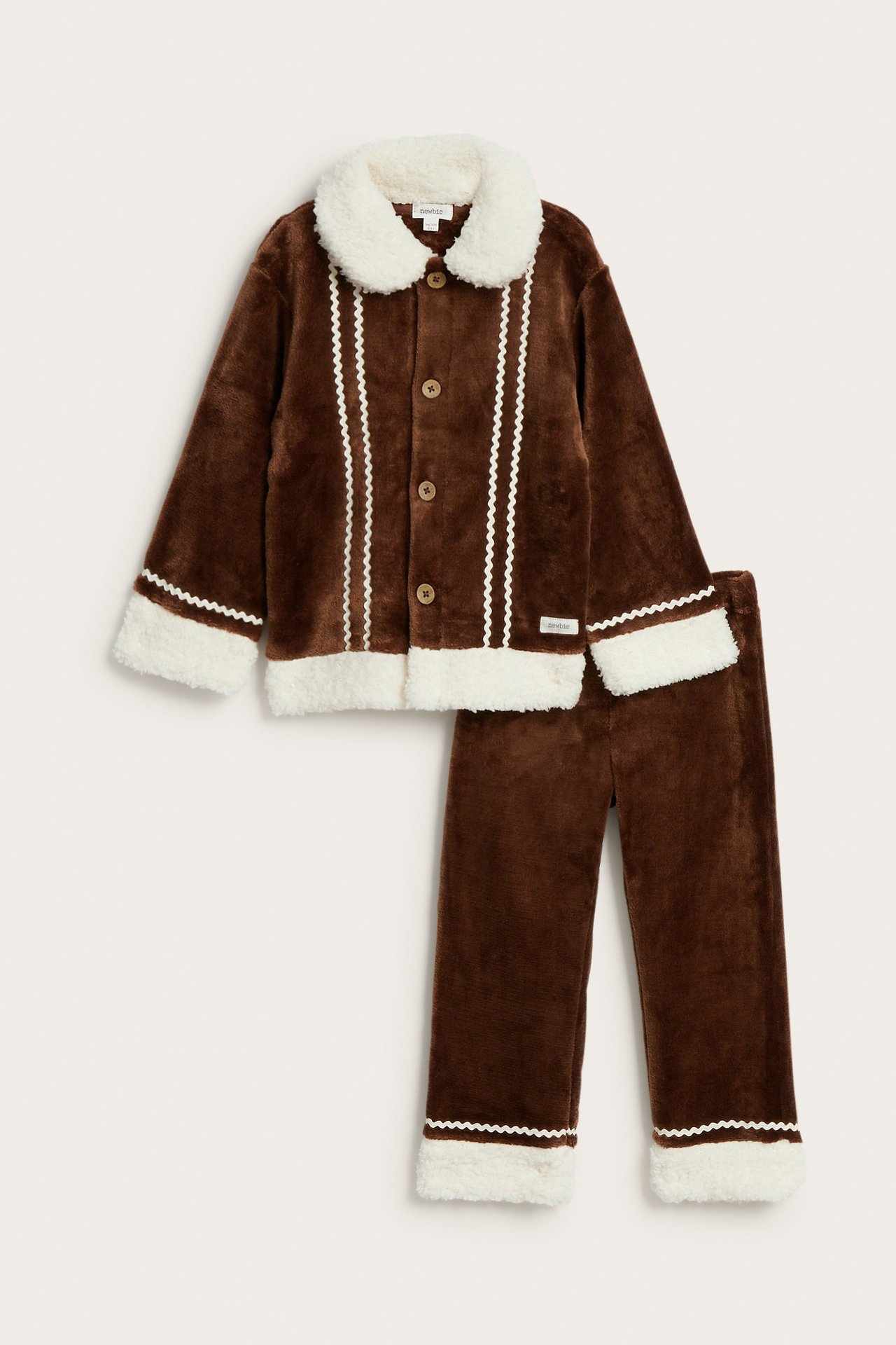 Vorderansicht eines braunen Plüsch-Kinderpyjama-Sets mit weißem Kunstfellbesatz und Zickzackdetails.