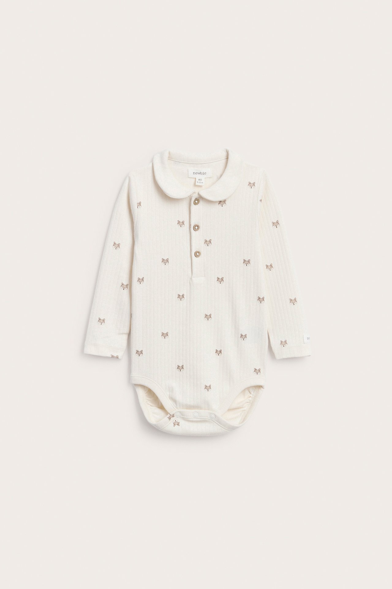 Front view of a cream ribbed baby bodysuit with a collar and small fox pattern.