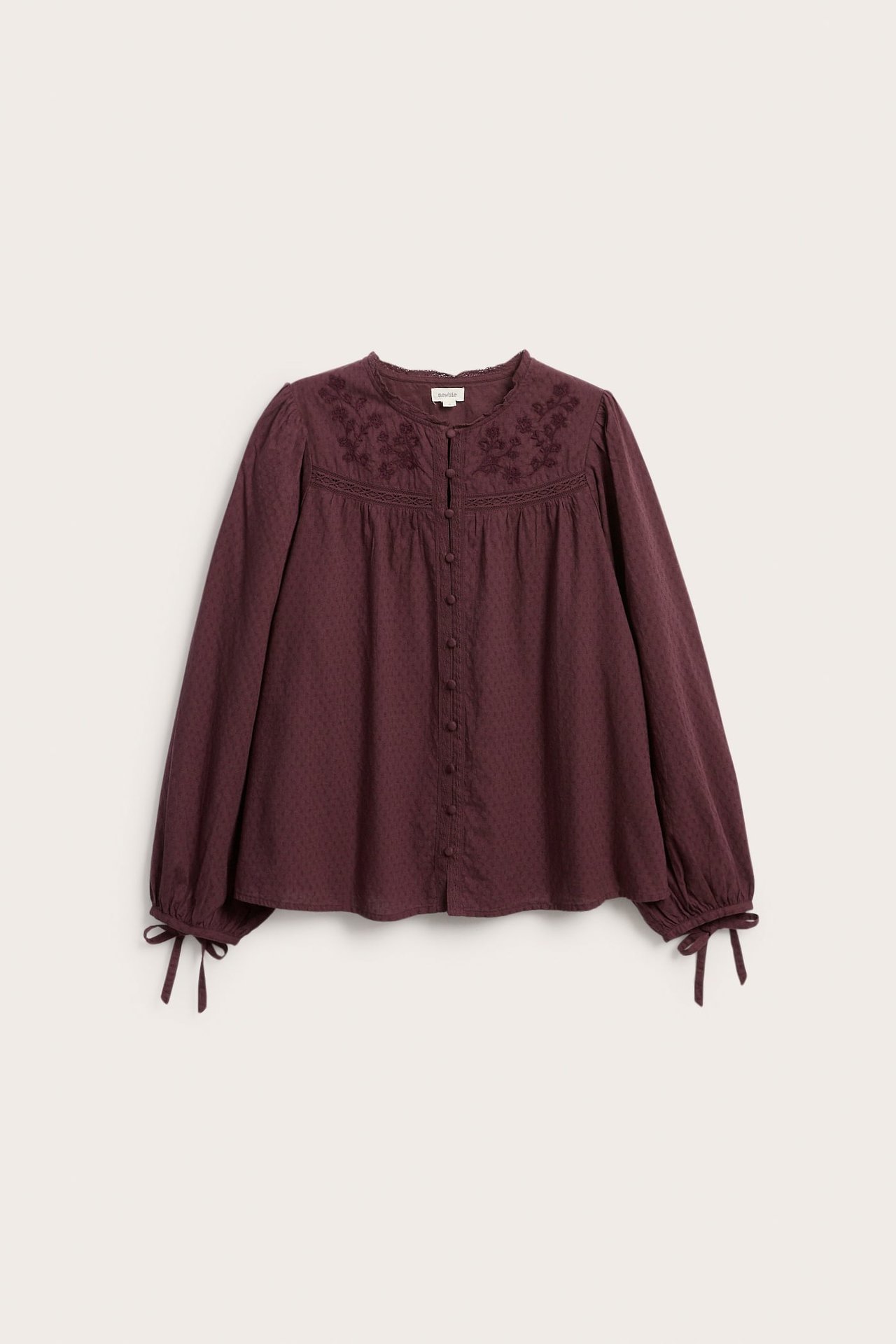 Front view of a dark red loose long-sleeved blouse with embroidery, button front, and tie cuffs.