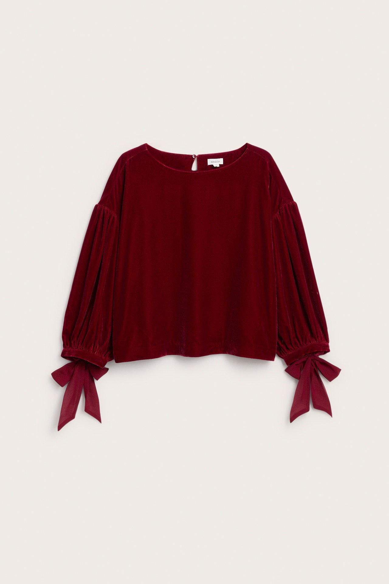 Vorderansicht einer dunkelroten Samtbluse mit Puffärmeln und Bindebündchen.
