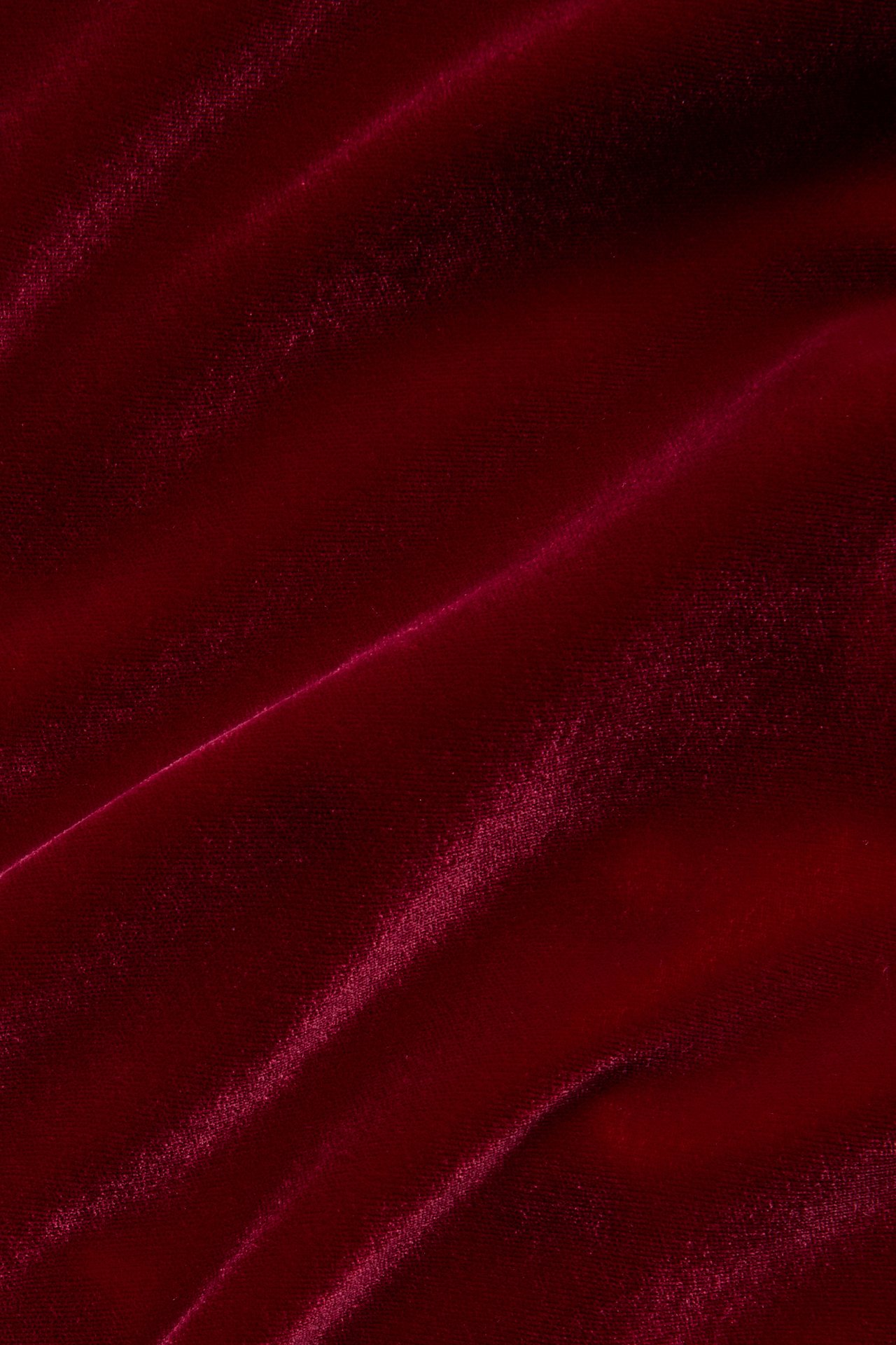 Close-up of draped red velvet fabric with soft folds.