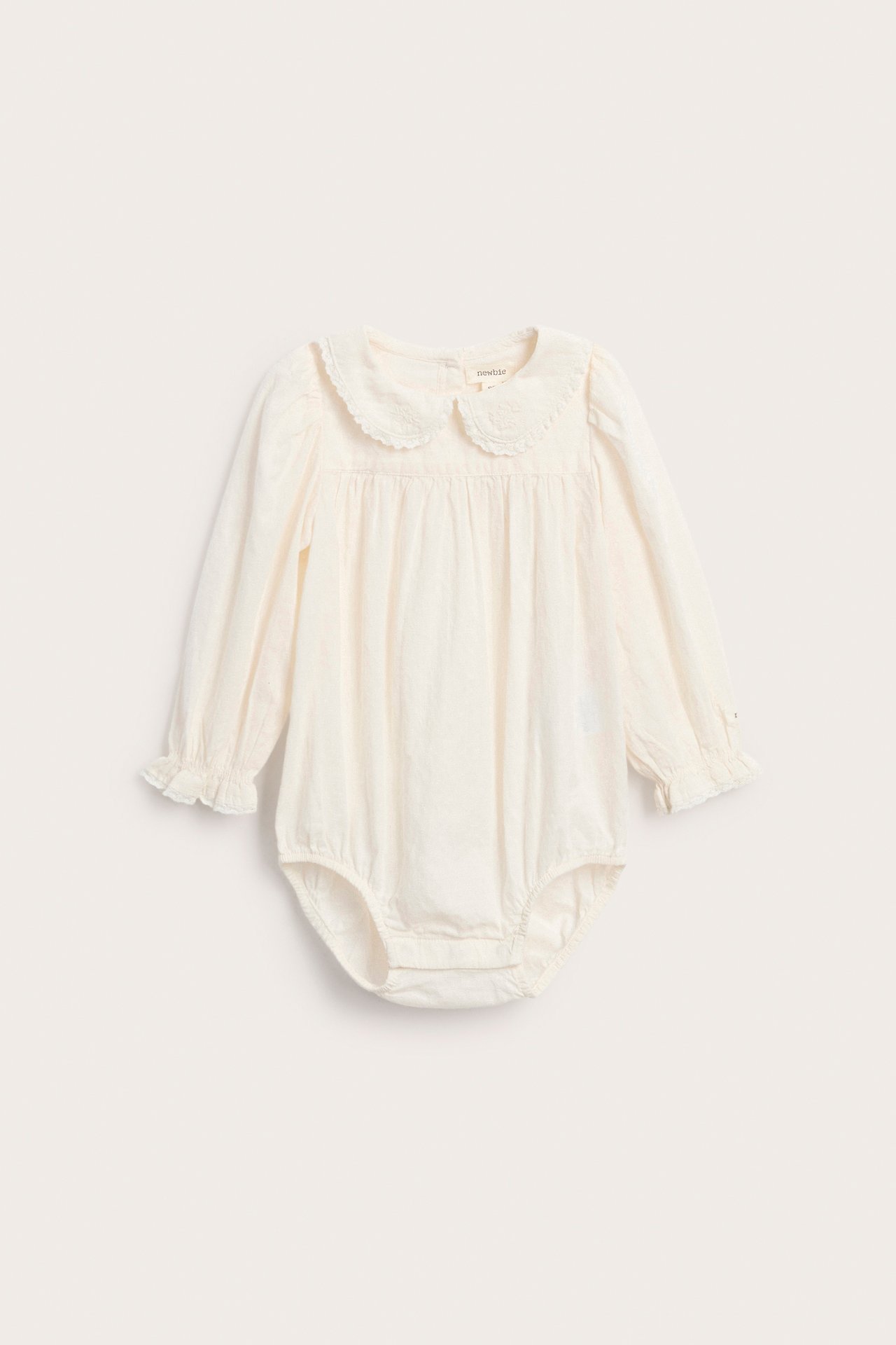 Front view of a baby's cream long-sleeved romper with an embroidered collar and ruffled cuffs.