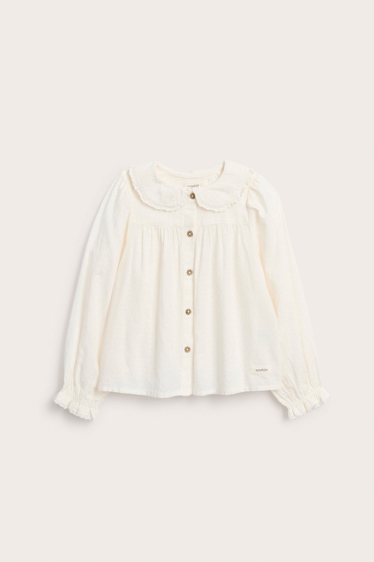 Front view of a kid's white long-sleeve blouse with embroidered Peter Pan collar and front buttons.