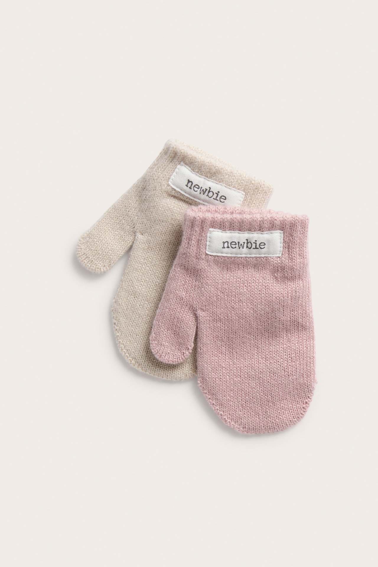 Nahaufnahme von rosa und beige gestrickten Babyfäustlingen.