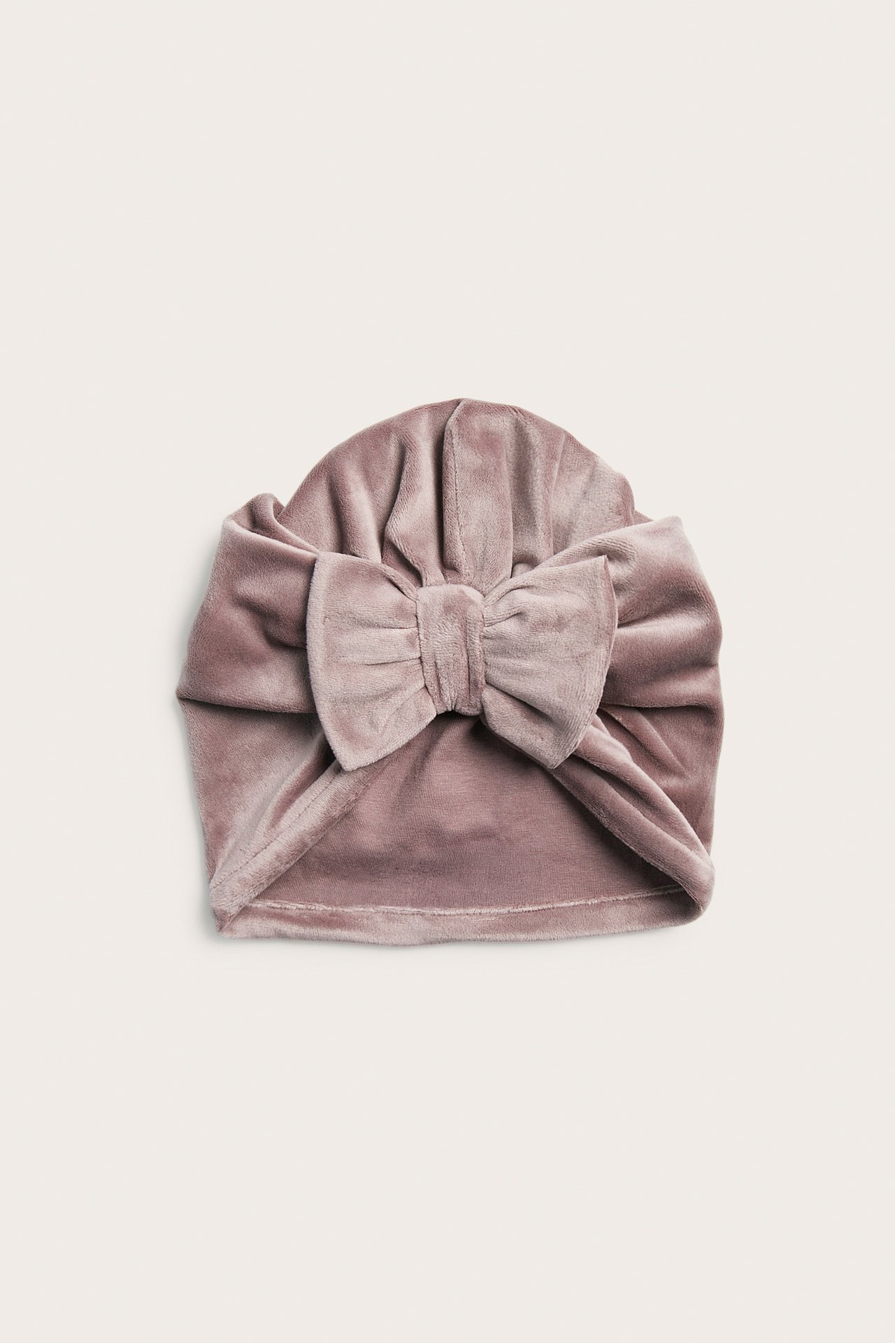 Vorderansicht eines Baby-Turbans aus altrosa Samt mit großer Schleife.