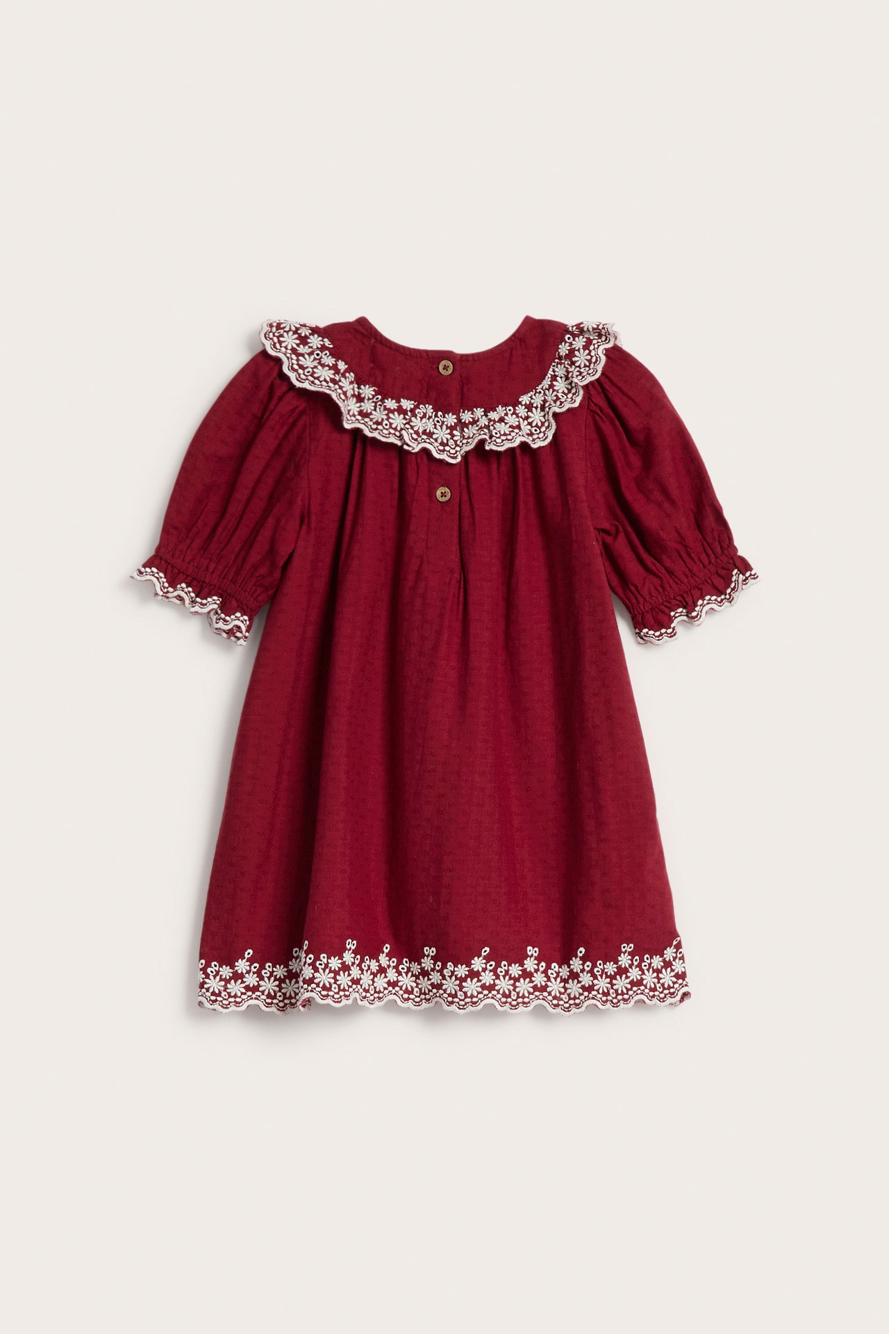 Kinderkleid von vorne in Dunkelrot mit weiß besticktem Rüschenkragen, Puffärmeln und besticktem Saum.