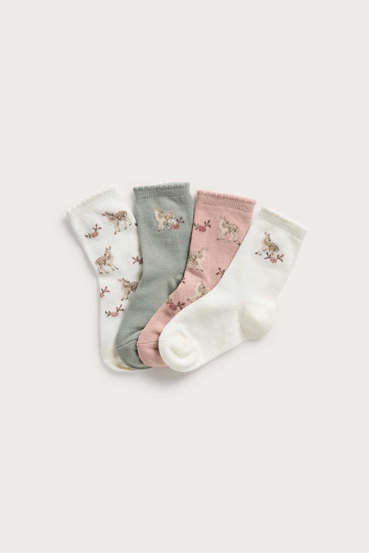 Draufsicht: Vier Paar gemusterte Kindersocken in Offwhite, Salbeigrün und Rosa mit Reh- und Blumenmustern.
