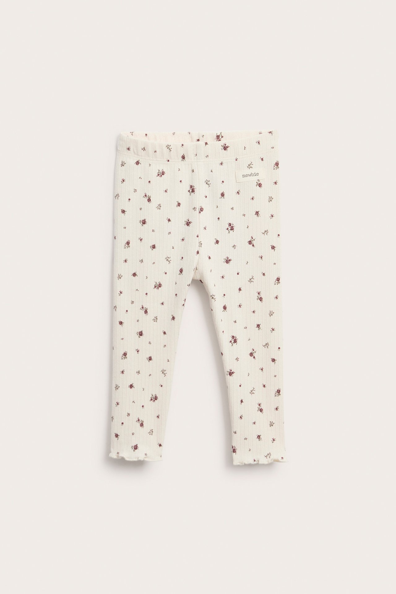 Cremefarbene gerippte Baby Leggings mit Blumenmuster und Rüschensaum, Vorderansicht.