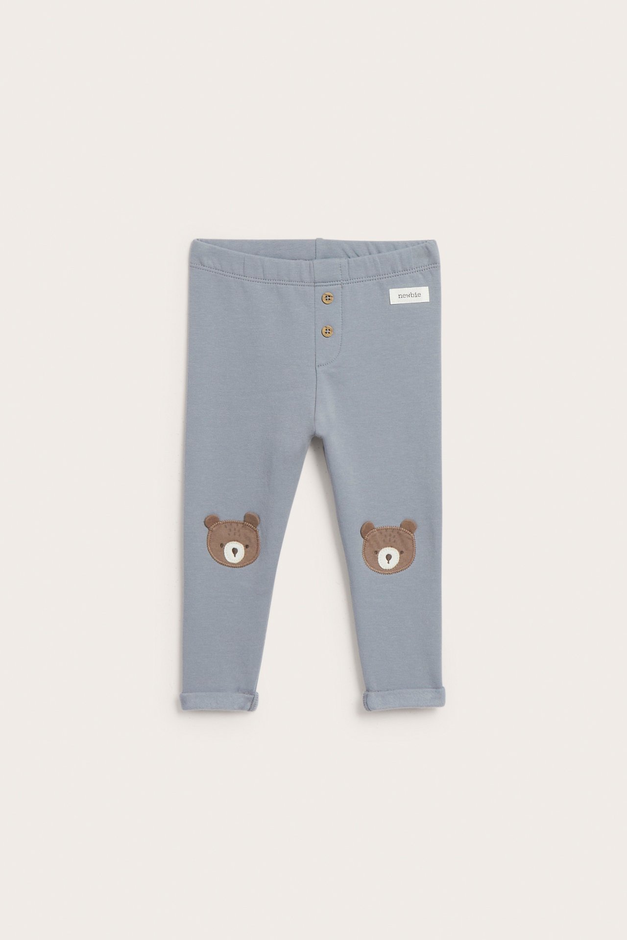 Front view of light blue baby leggings with two buttons and two brown bear knee patches.