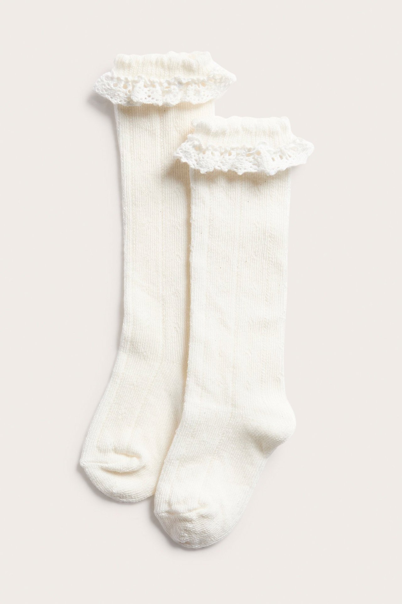 Front view of off-white pointelle knit knee socks with ruffled lace trim at the top.