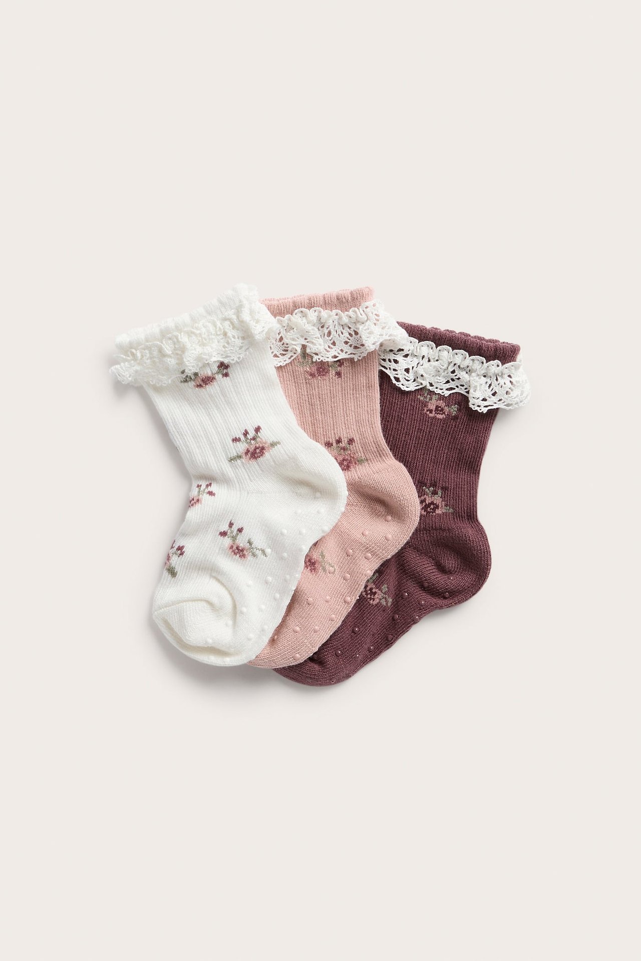 Front view of three pairs of baby socks in white, pink, and burgundy, with lace cuffs and floral embroidery.