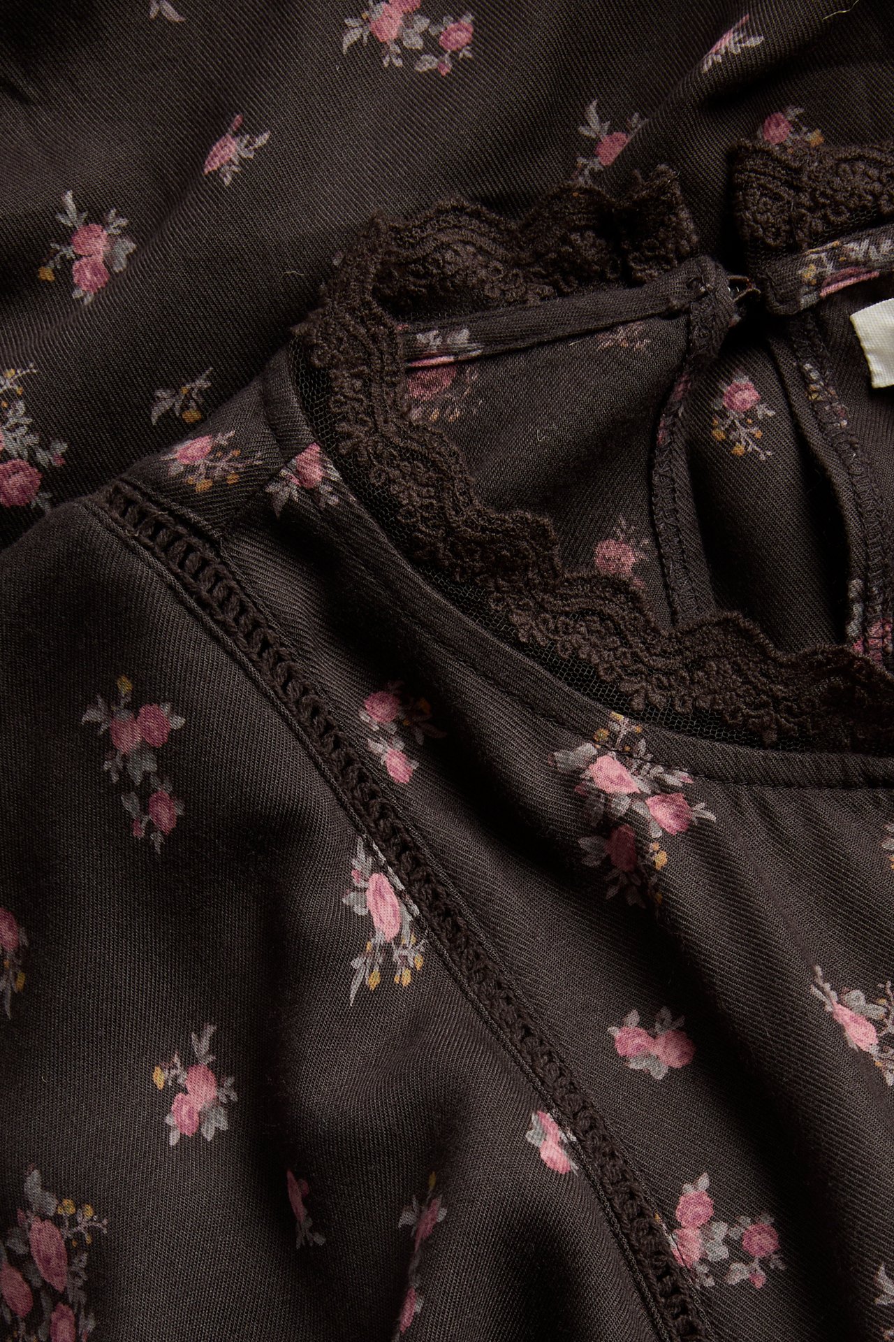 Close-up of a dark brown floral top with a ruffled lace neckline and stitched detail.