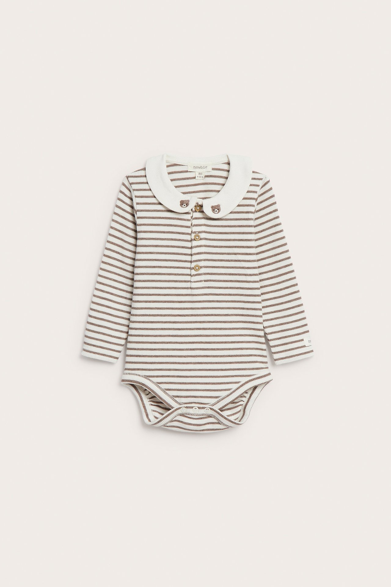 Vorderansicht eines gestreiften Baby-Bodys in Creme und Braun mit weißem Kragen und Bärenknöpfen.