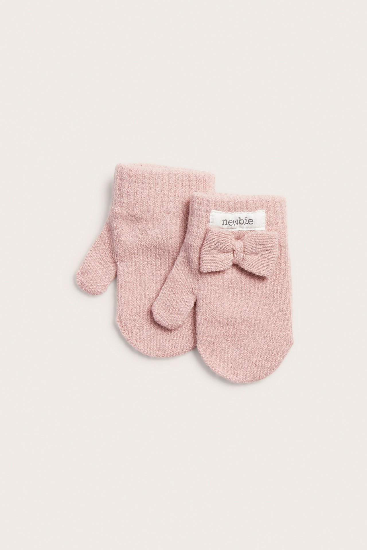 Vorderansicht von zwei rosa gestrickten Babyfäustlingen, einer mit Schleife und weißem Markenetikett.