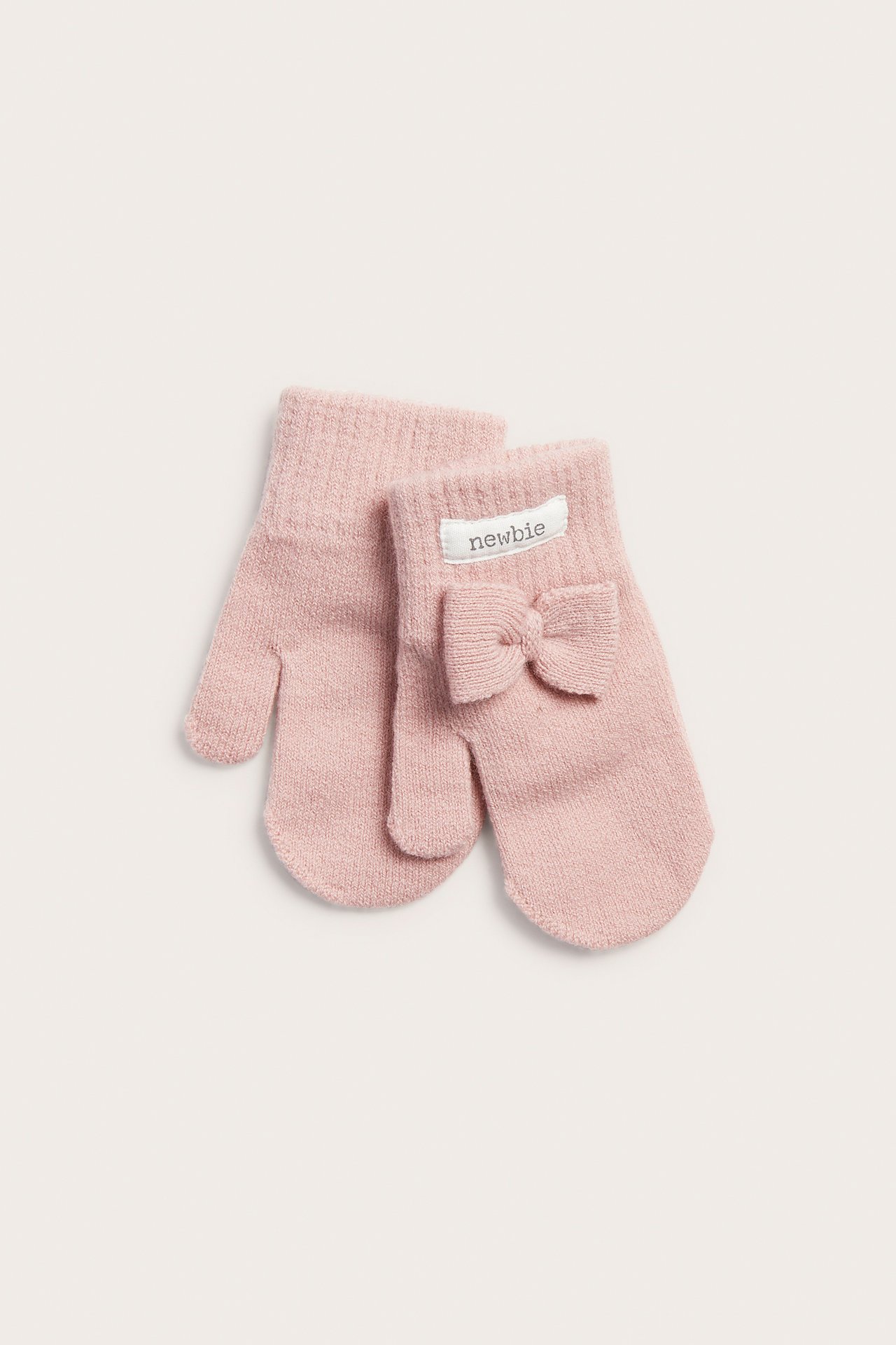 Vorderansicht eines Paares rosa gestrickter Babyfäustlinge, einer mit 'newbie'-Etikett und Schleife.