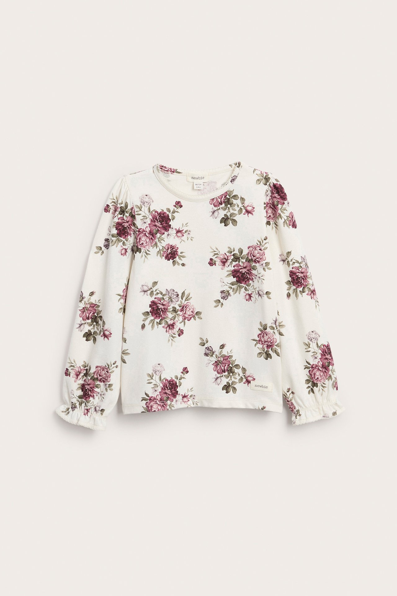 Vorderansicht eines cremefarbenen Langarm-Shirts für Kinder mit Blumenmuster und Rüschenbündchen.