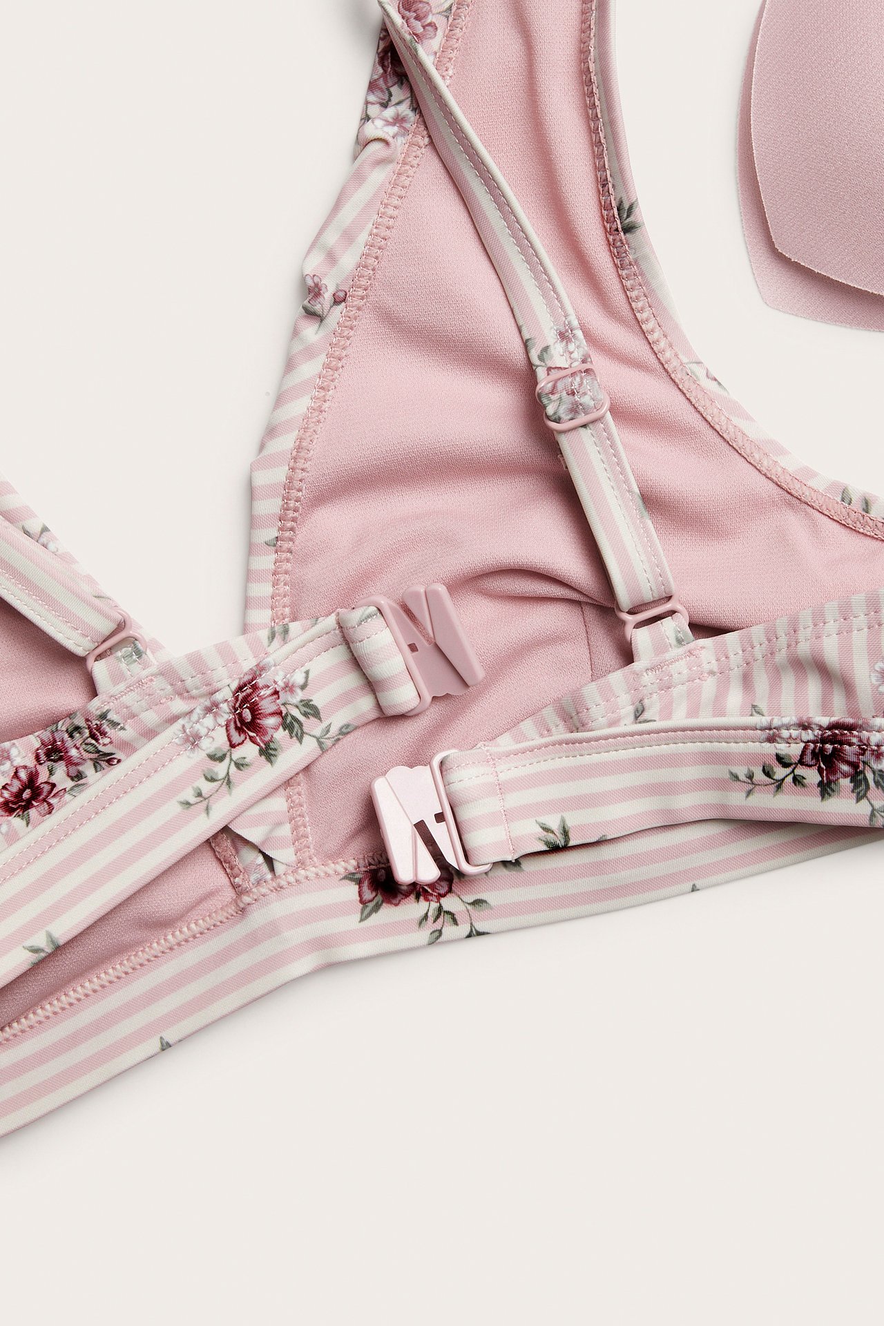 Close-up of a pink and white striped floral bikini top with adjustable straps.