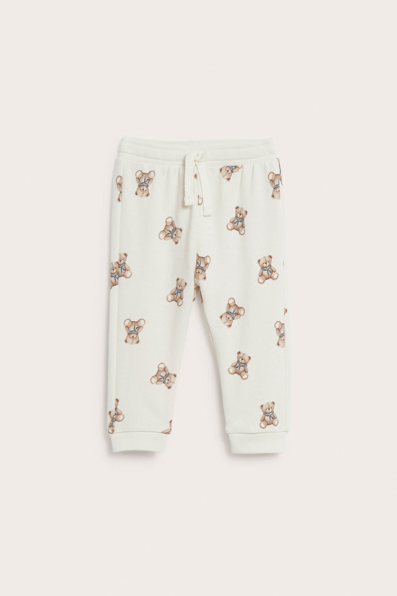 Front view of baby off-white teddy bear print sweatpants with a drawstring waist and ribbed cuffs.