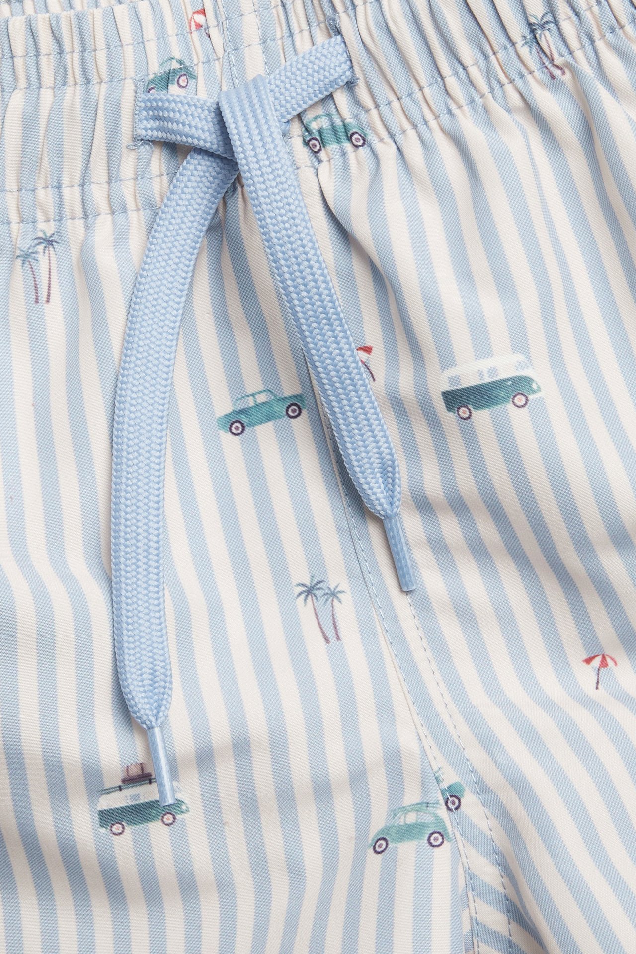 Close-up of kid's blue and white striped swim shorts with car print and a light blue drawstring.