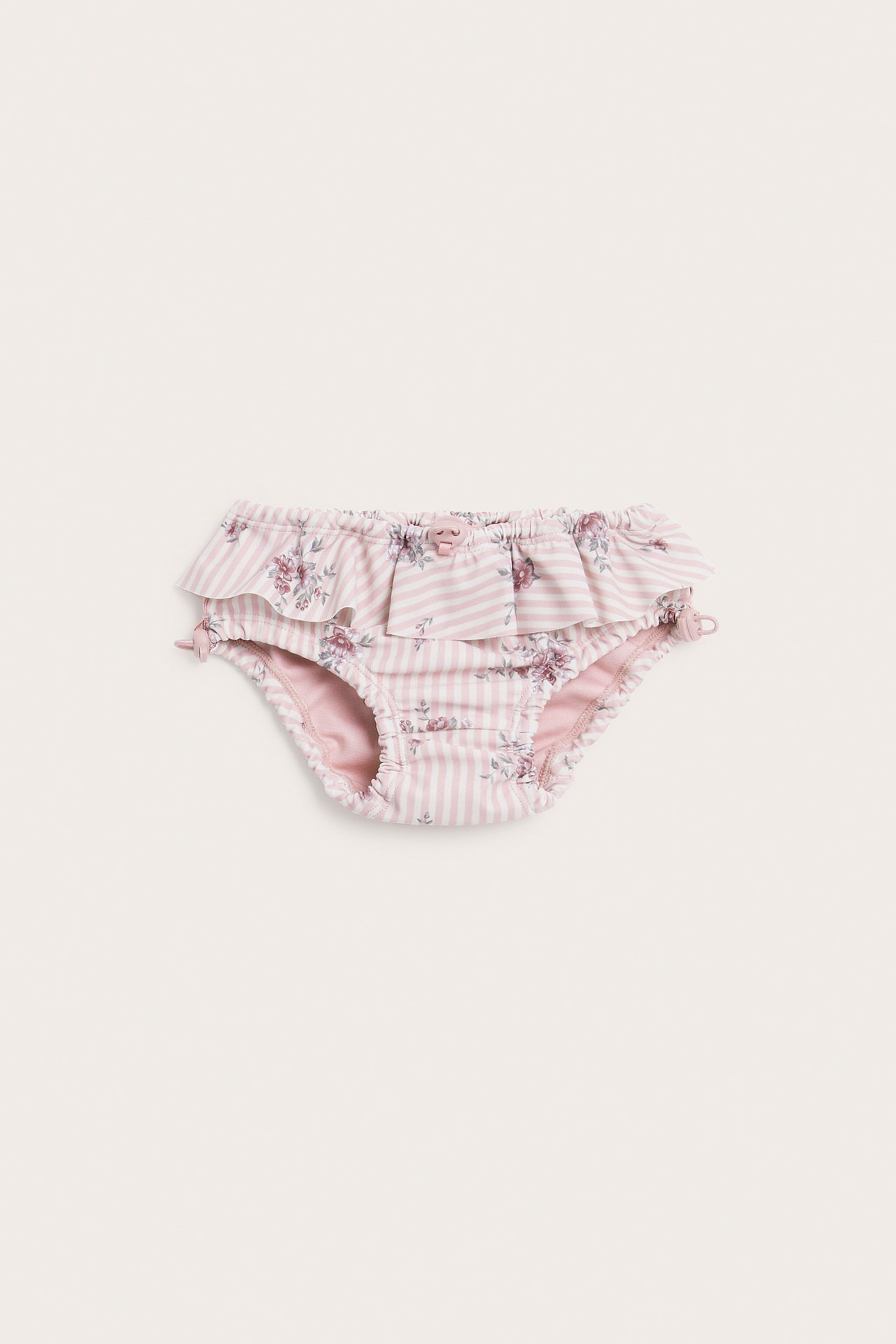 Vorderansicht, gerüschter Babyslip mit rosa-weißen Streifen und Blumenmuster.