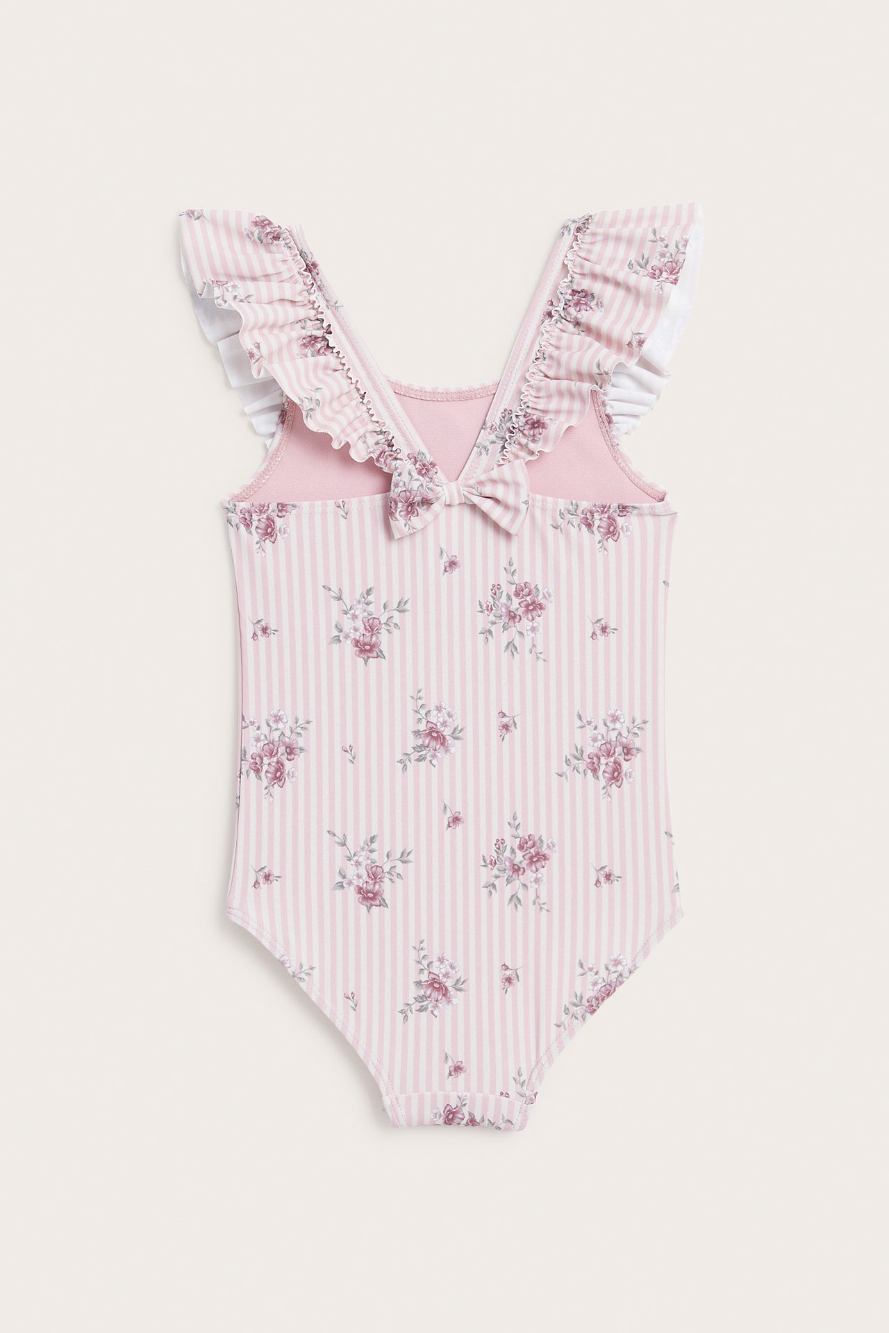 Back view of a kid's pink and white striped swimsuit with floral print, ruffles, and a bow.