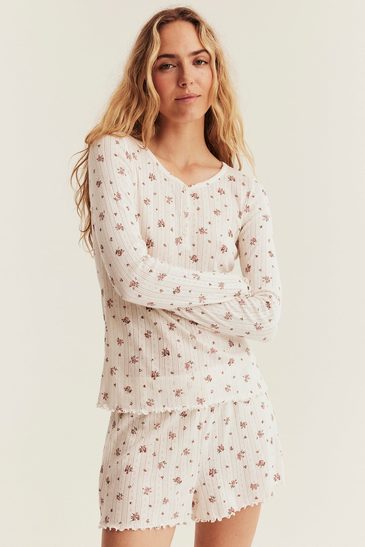 Vorderansicht, Frau in einem weißen gerippten Blumen-Pyjama-Set mit Langarmshirt und Shorts.