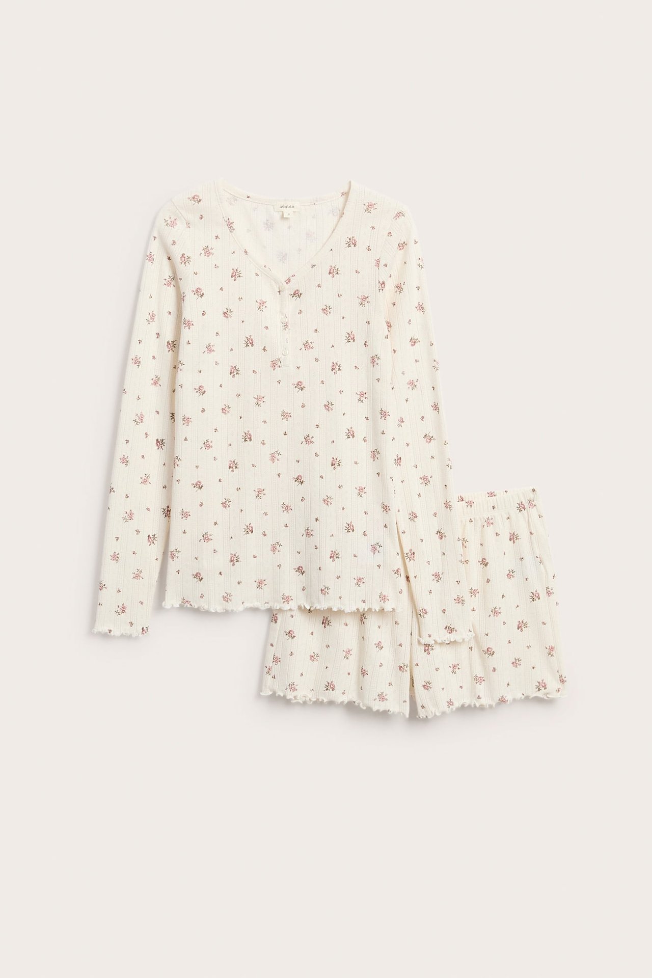 Vorderansicht eines cremefarbenen gerippten Pyjama-Sets mit Blumenmuster, Langarmshirt und Rüschenshorts.