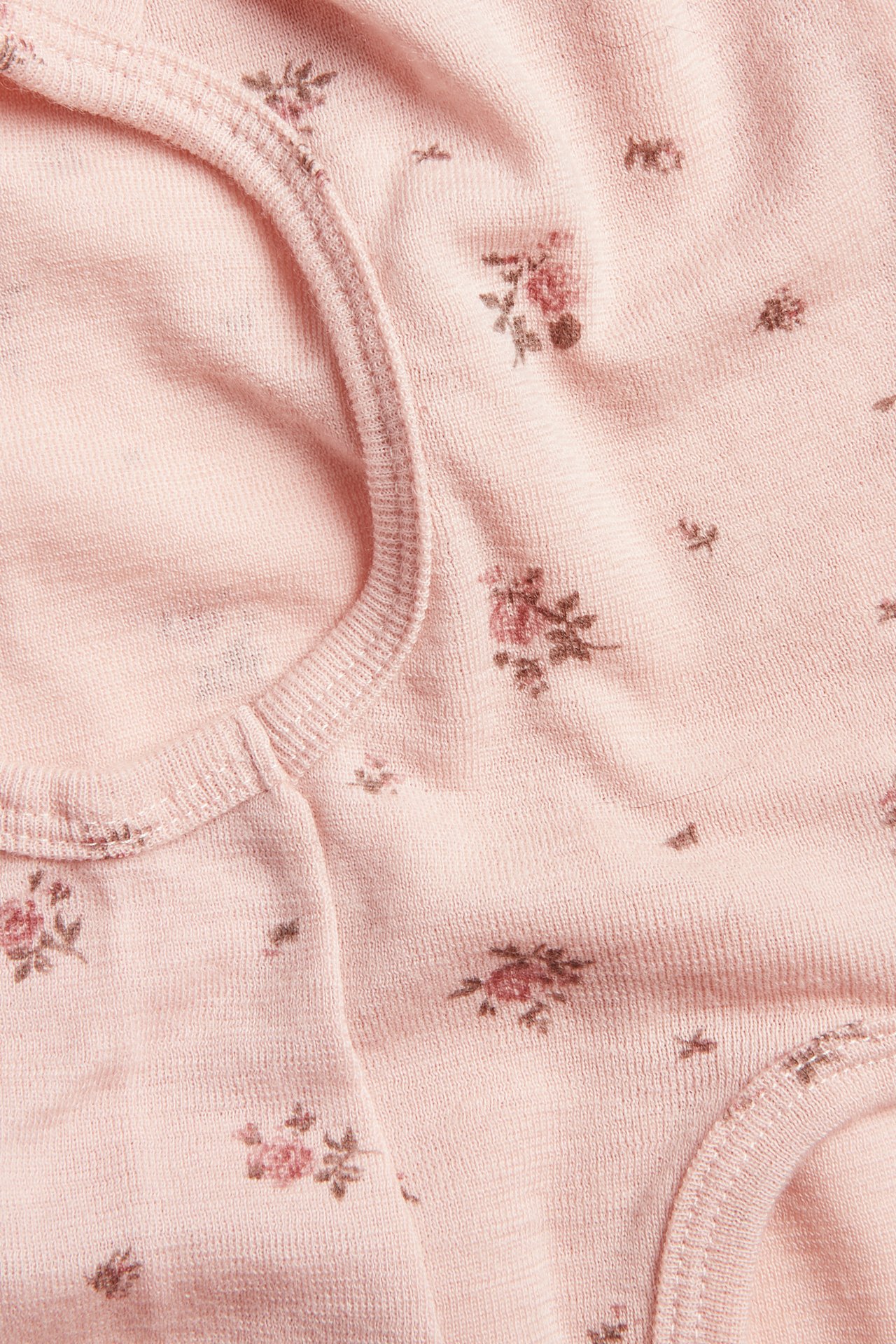 Close-up of a light pink baby jersey top with a ribbed neckline and floral print.