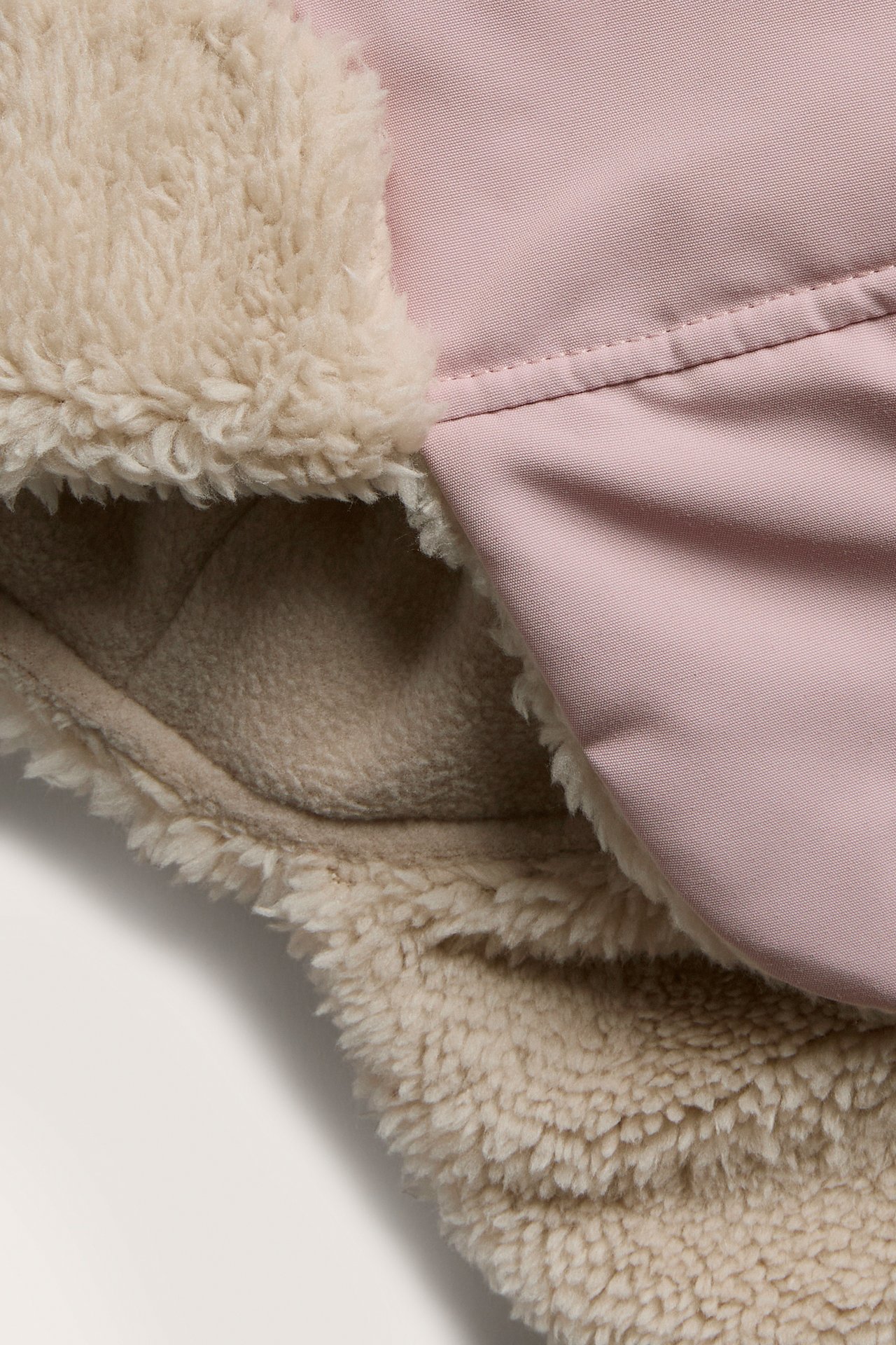 Nahaufnahme eines rosa Kleidungsstücks mit beigem Kunstfellfutter.