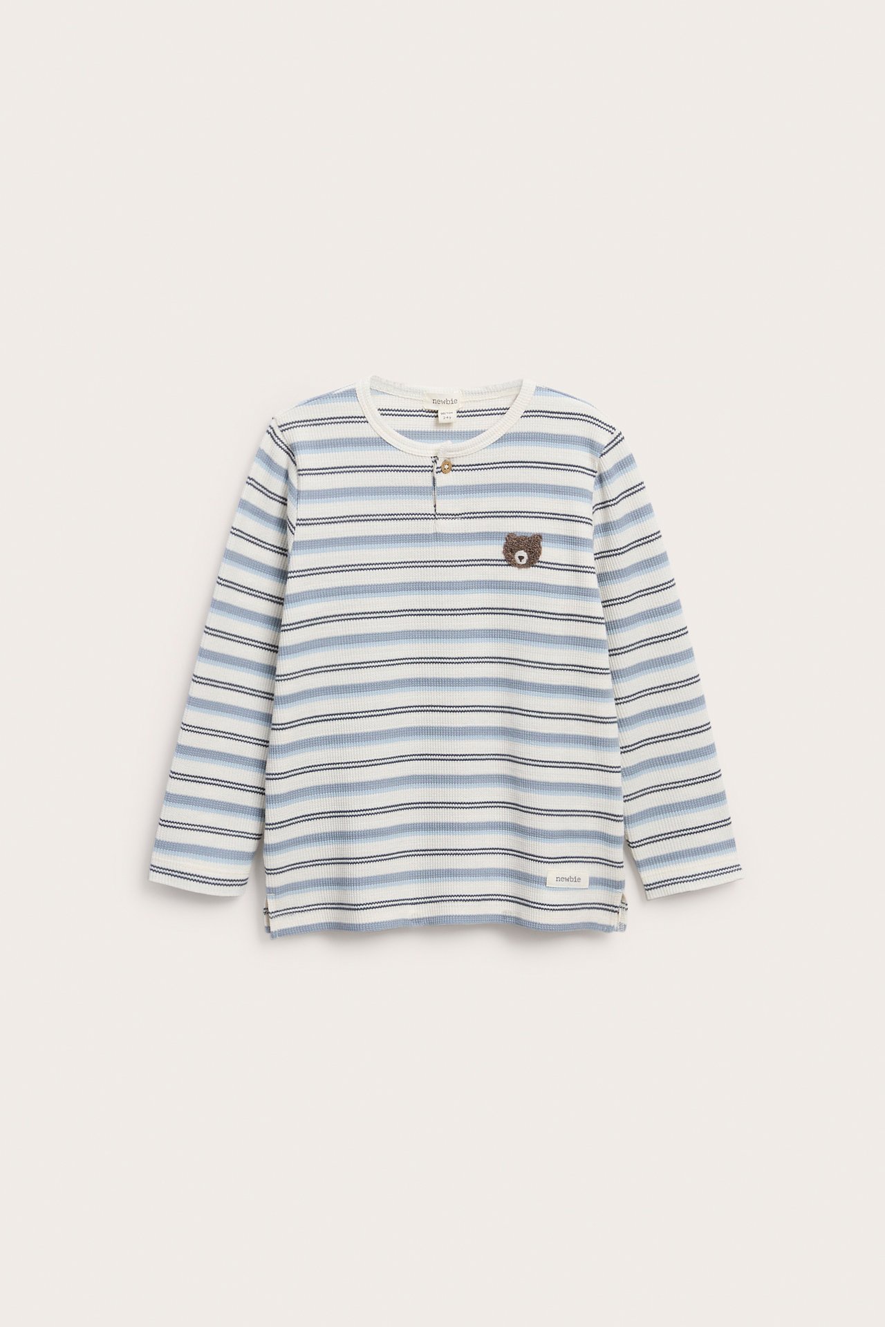 Front view of a kid's striped blue and white ribbed long-sleeve top with a bear embroidery.
