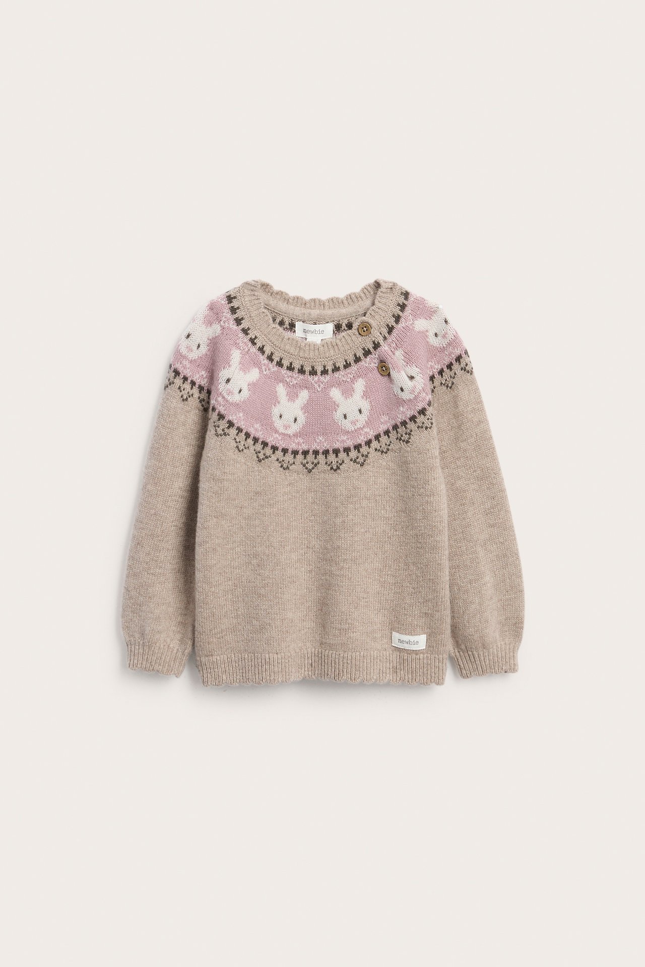 Vorderansicht eines beigen Strickpullovers für Babys mit rosa Fair-Isle-Hasenmuster und zwei braunen Knöpfen.