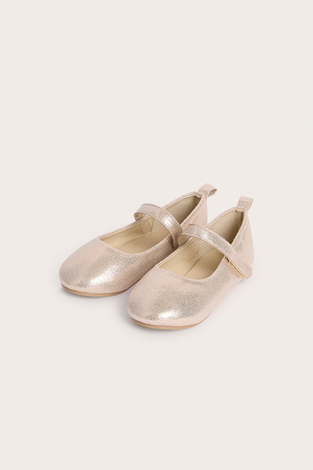 Draufsicht auf zwei metallische roségoldene Kinder-Ballerinas mit Ristriemen.