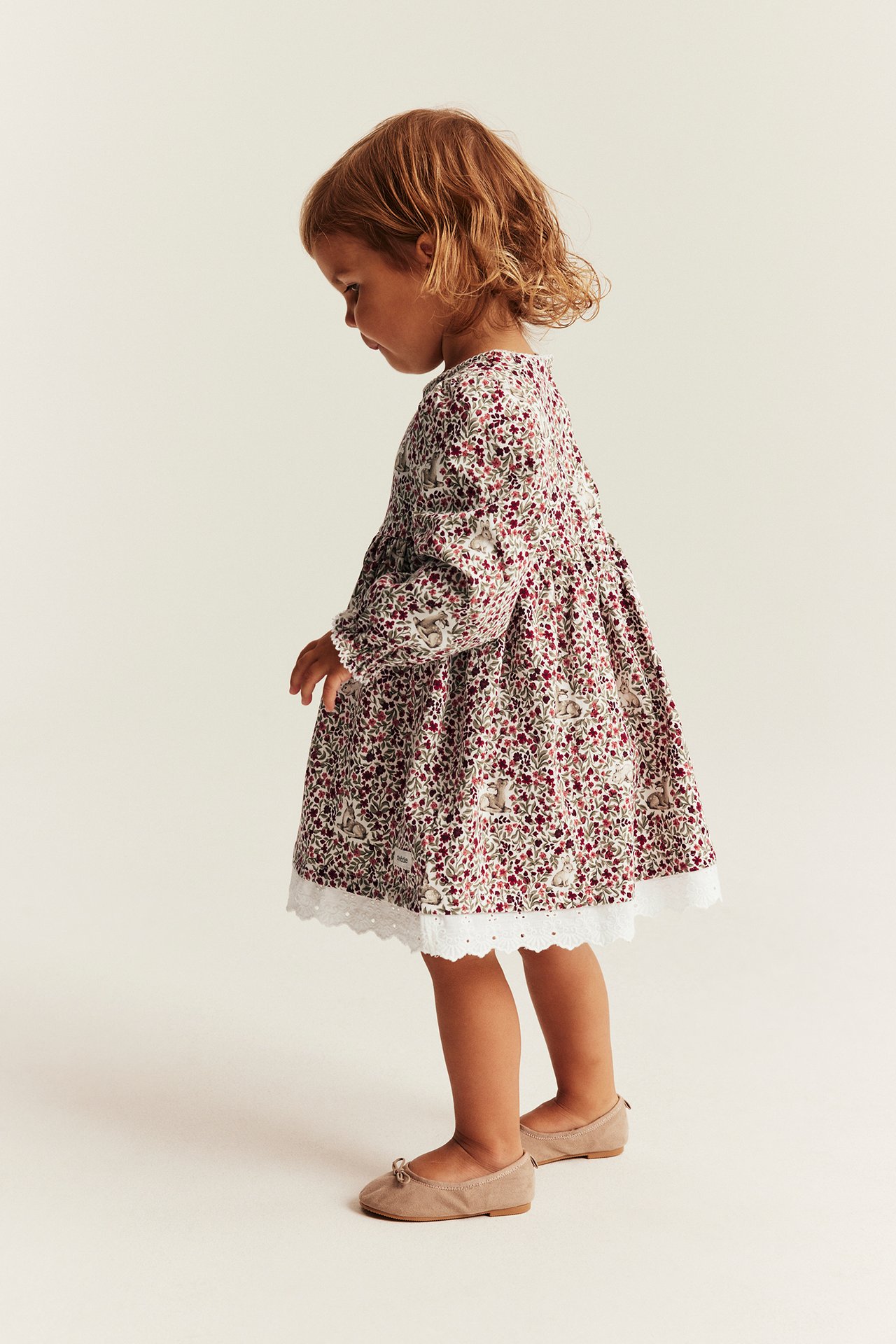 Kinderkleid, langärmlig, Blumen- und Hasenmuster, Spitzenbesatz und beige Ballerinas.
