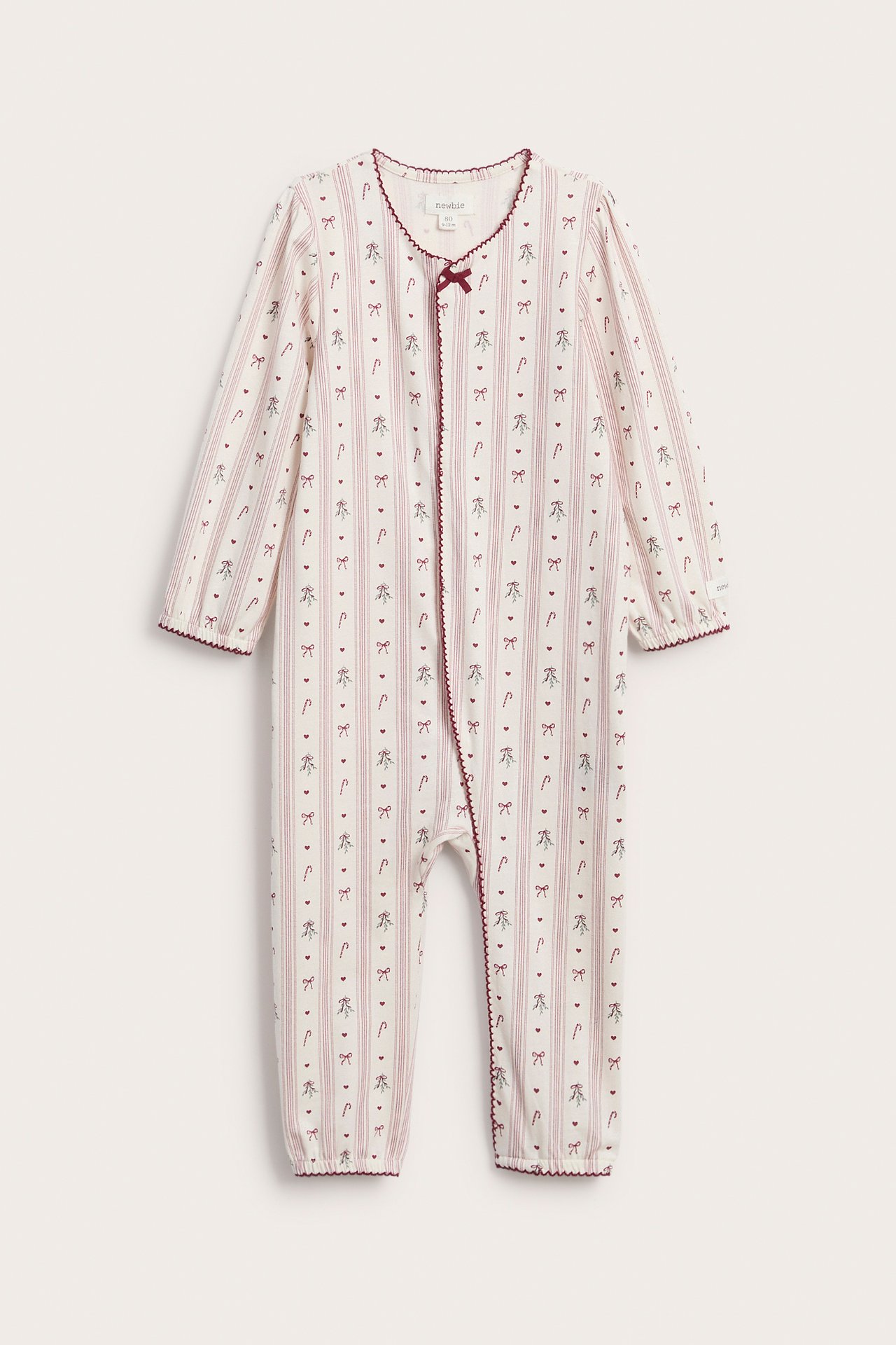 Front view of a baby's white long-sleeved romper with red stripes, bows, hearts, and candy cane pattern.