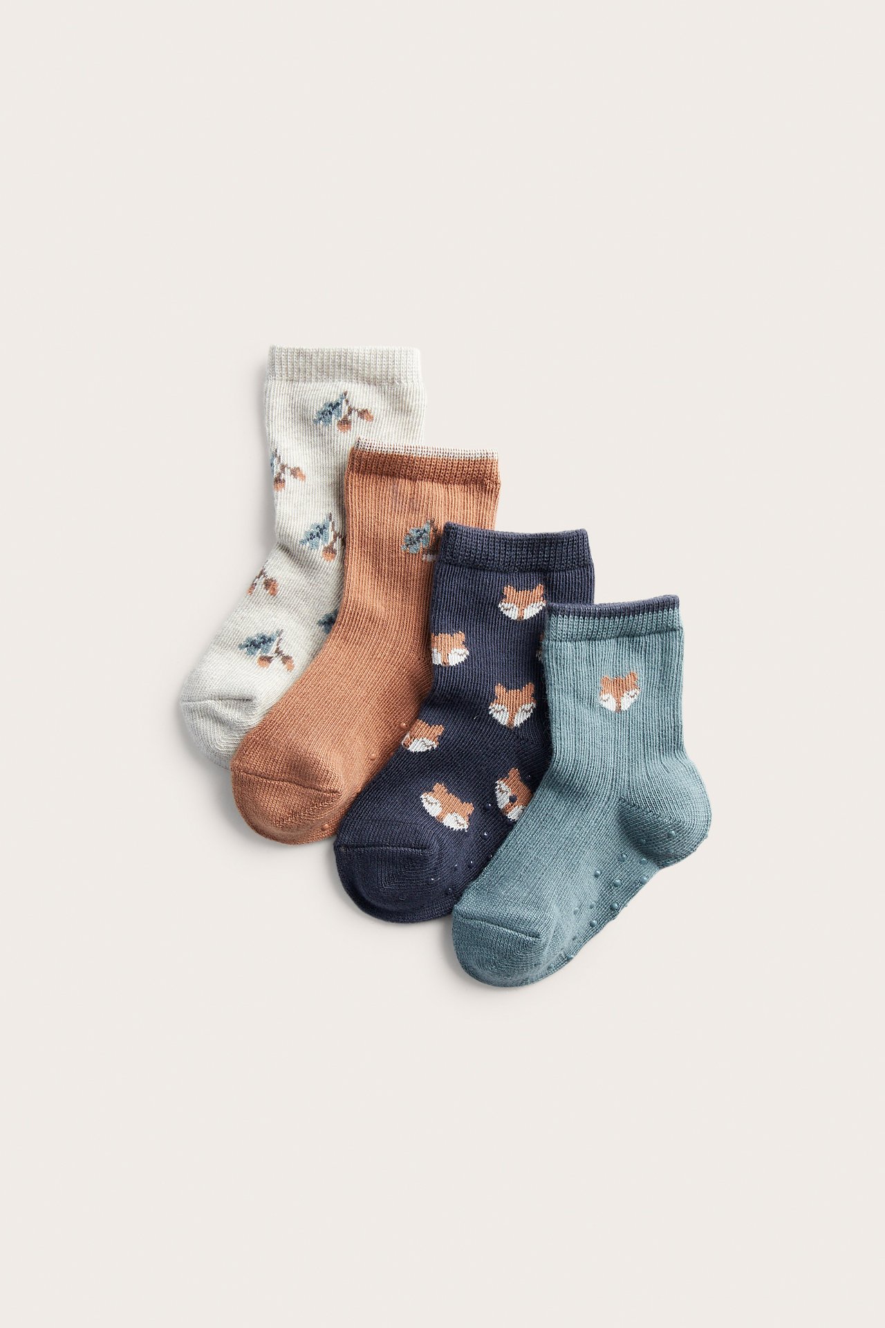 View of four pairs of baby socks: ribbed teal with fox, navy fox, cream floral, orange floral.