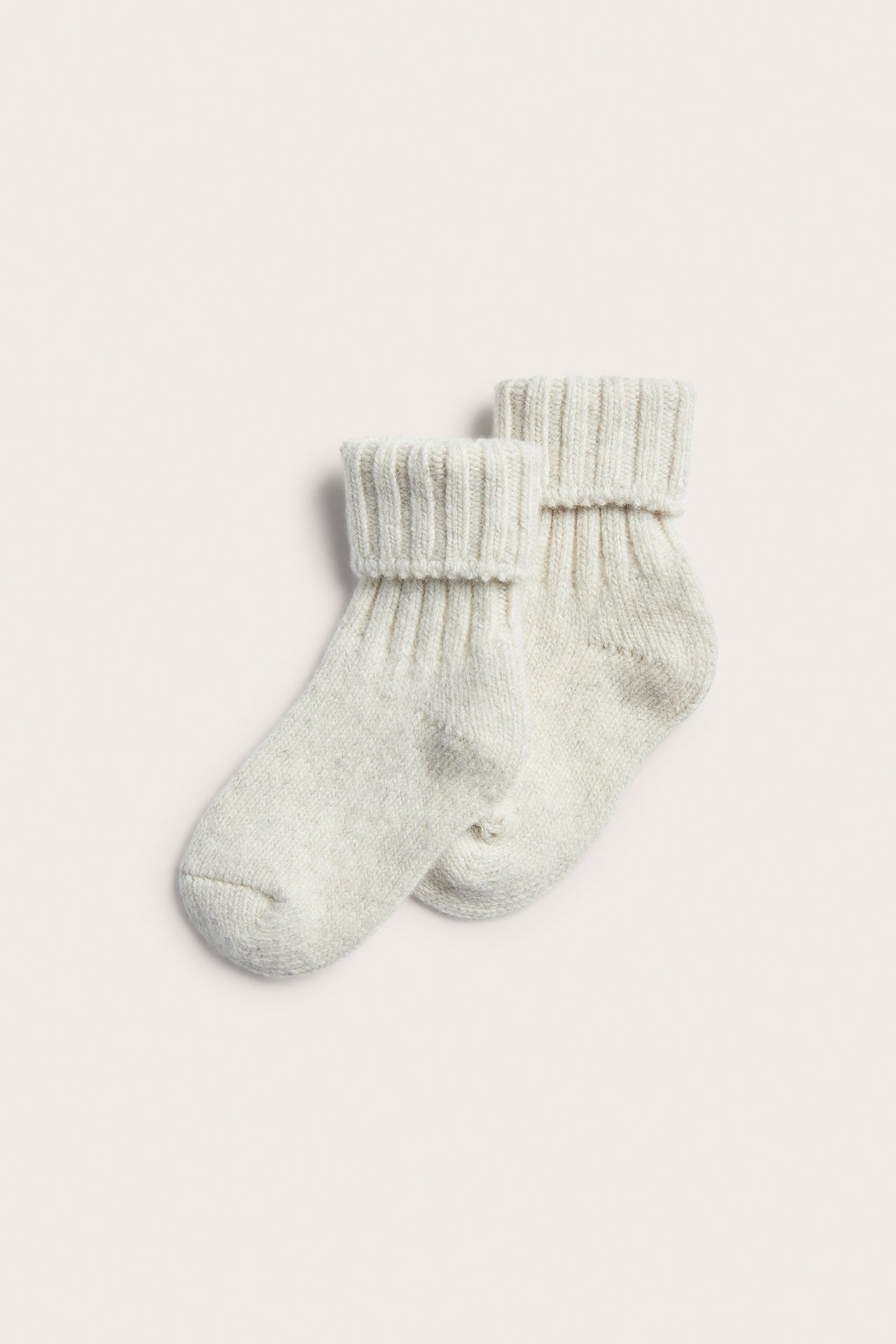 Erhöhte Ansicht eines Paares hellbeiger Strickstrümpfe mit Rippenbündchen.