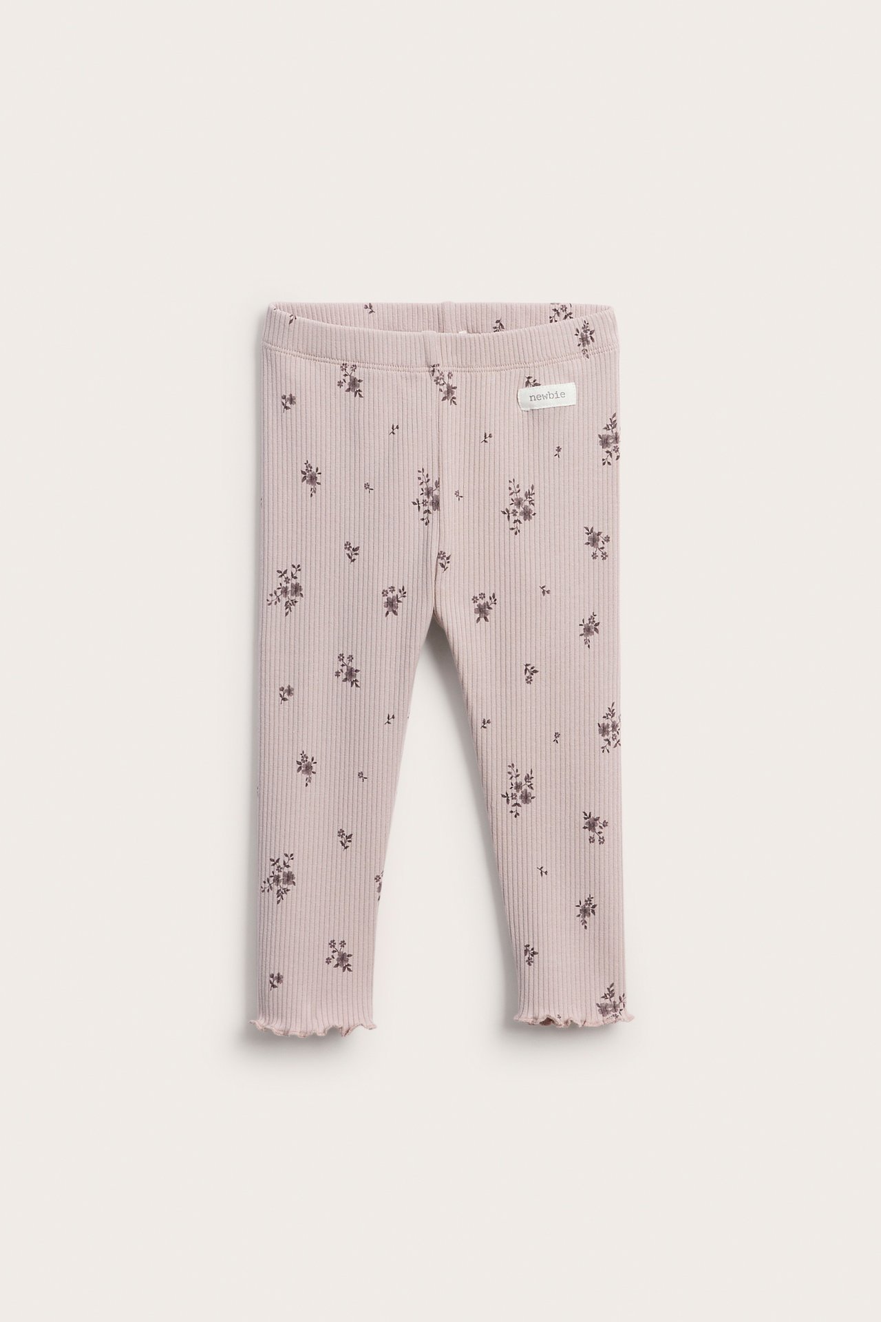 Front view of ribbed baby leggings in light pink with a dark floral print and lettuce hems.
