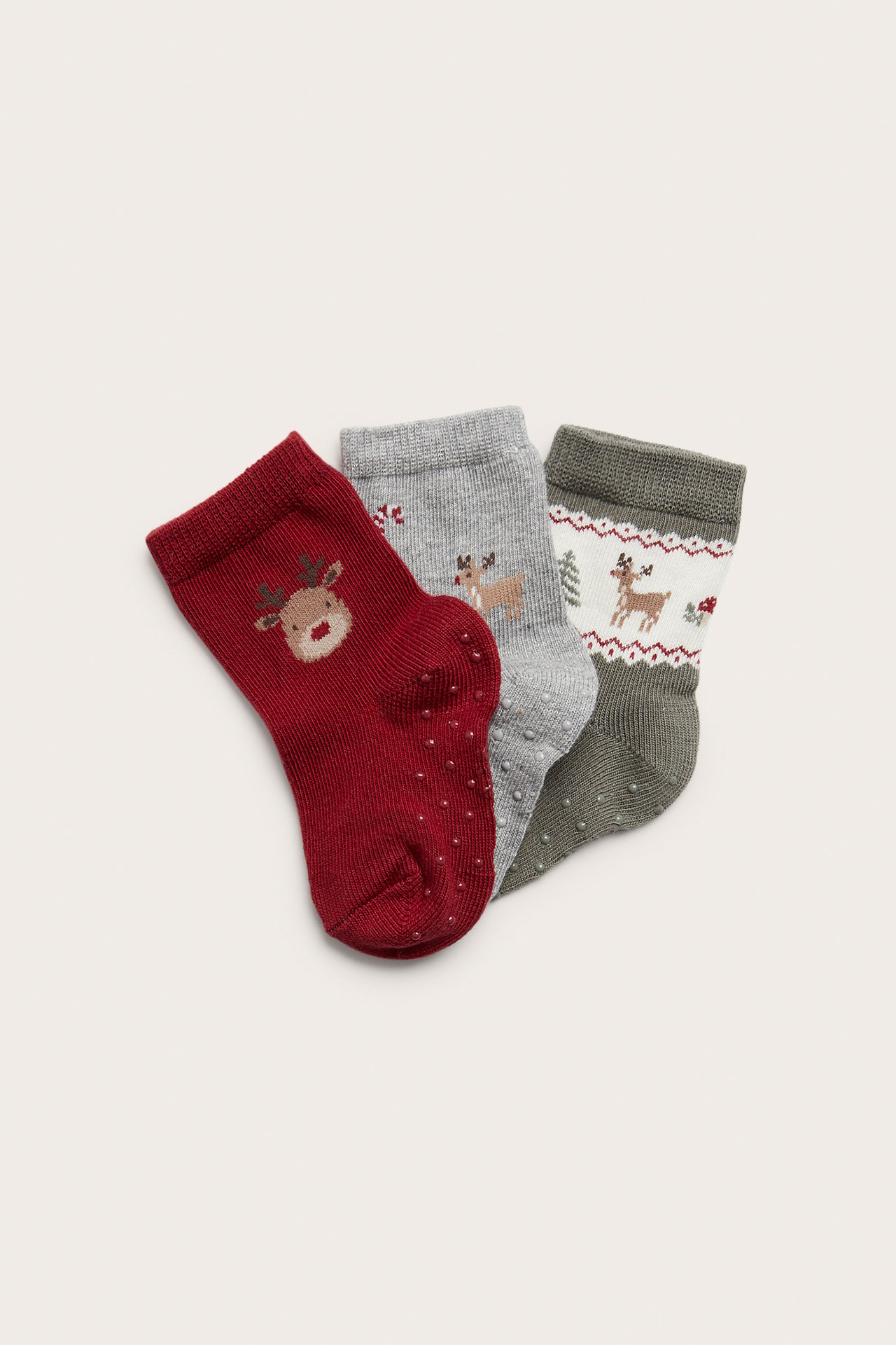 Nahaufnahme von drei Paar Baby-Antirutschsocken: rote Rentiere, graue Rentiere, weiß-graue Rentiere.